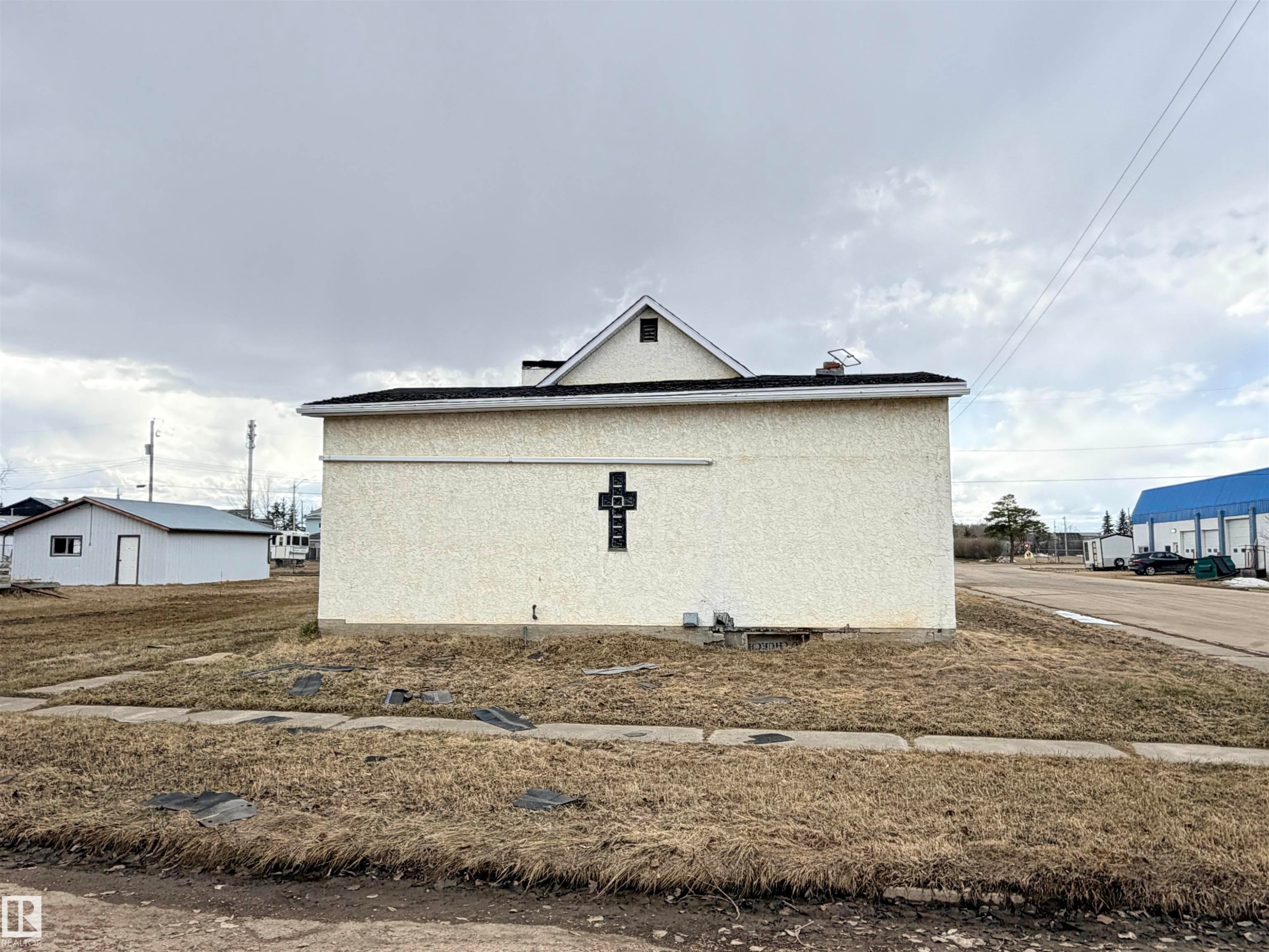 Stucco exterior featuring an ornamental cross detail - 5036 49 Street, Clyde, AB - Outdoor