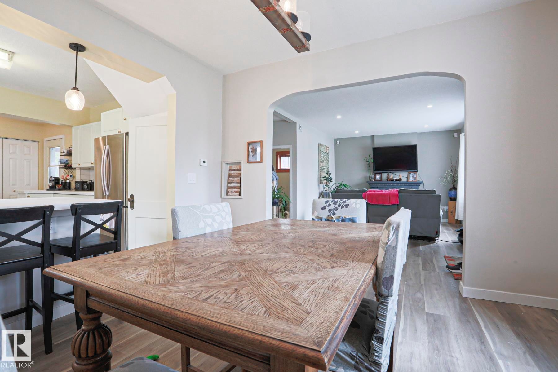 Dining area featuring a wood-finish table, arched doorway, and light wood-finish flooring - 5113 53 Avenue, Stony Plain, AB - Indoor Photo Showing Dining Room