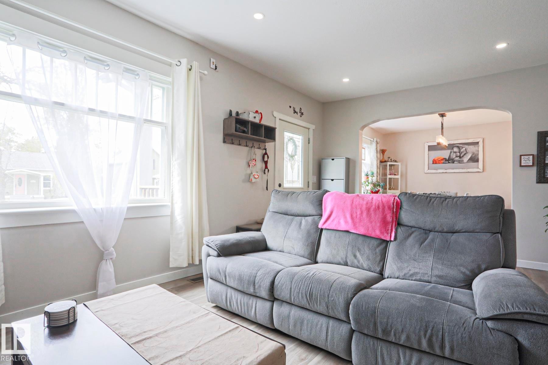 Bright interior space featuring recessed ceiling lighting, light gray wall paint, and wood-finish flooring - 5113 53 Avenue, Stony Plain, AB - Indoor Photo Showing Living Room