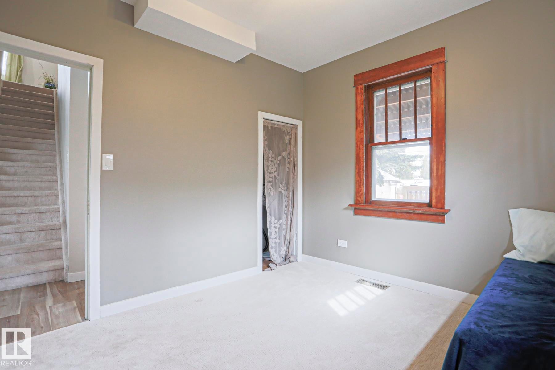Plush carpeting, neutral wall tones, white trim, and a wood-framed window with a multi-pane upper sash - 5113 53 Avenue, Stony Plain, AB - Indoor Photo Showing Other Room