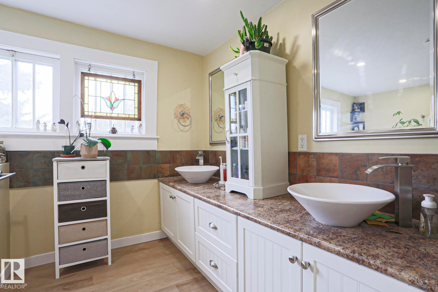 Dual vessel sinks with modern chrome faucets, complemented by a granite-look countertop - 5113 53 Avenue, Stony Plain, AB - Indoor Photo Showing Bathroom