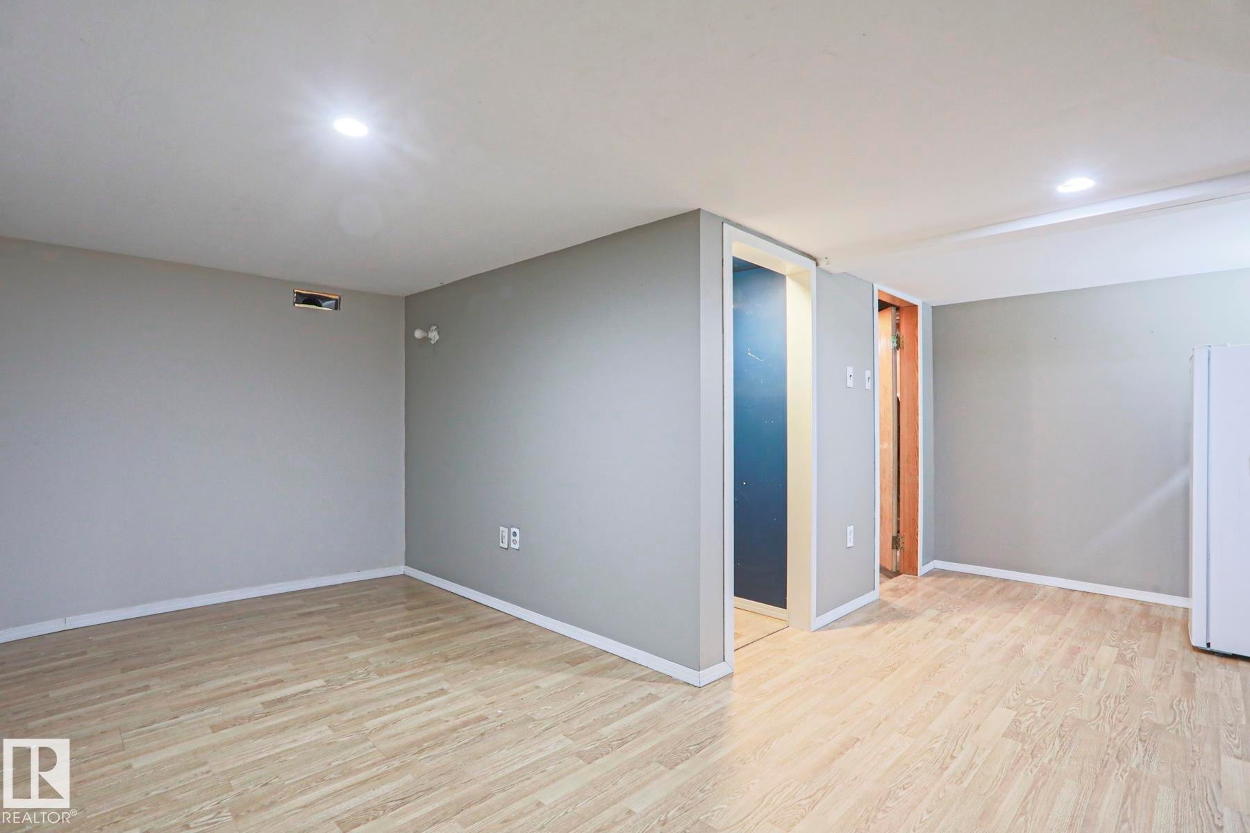 Spacious room featuring light wood-finish flooring, recessed lighting, and neutral grey walls with white trim - 5113 53 Avenue, Stony Plain, AB - Indoor Photo Showing Other Room