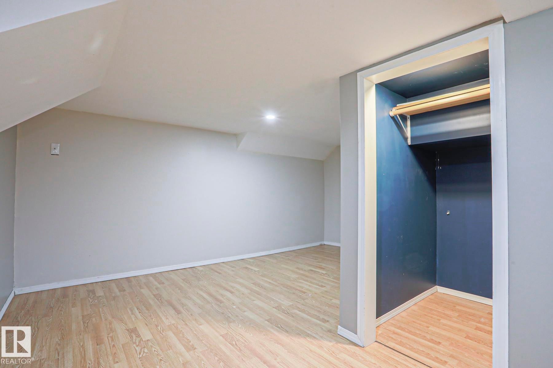 Spacious room featuring wood-finish flooring, light grey walls, recessed lighting, and a closet with a built-in rod and shelf - 5113 53 Avenue, Stony Plain, AB - Indoor