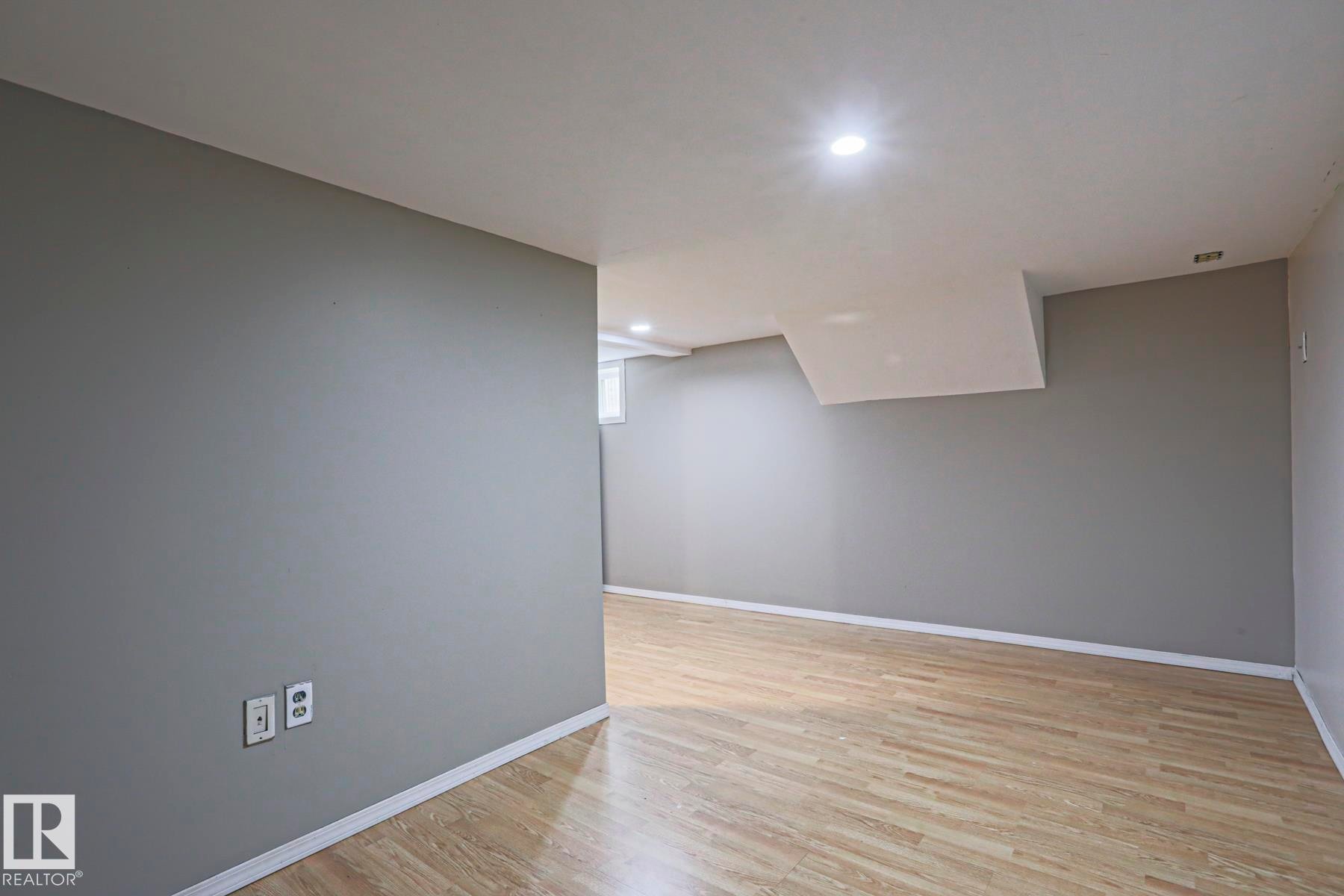 Open-concept room featuring neutral gray walls, light wood-finish flooring, white trim, and recessed ceiling lighting - 5113 53 Avenue, Stony Plain, AB - Indoor Photo Showing Other Room