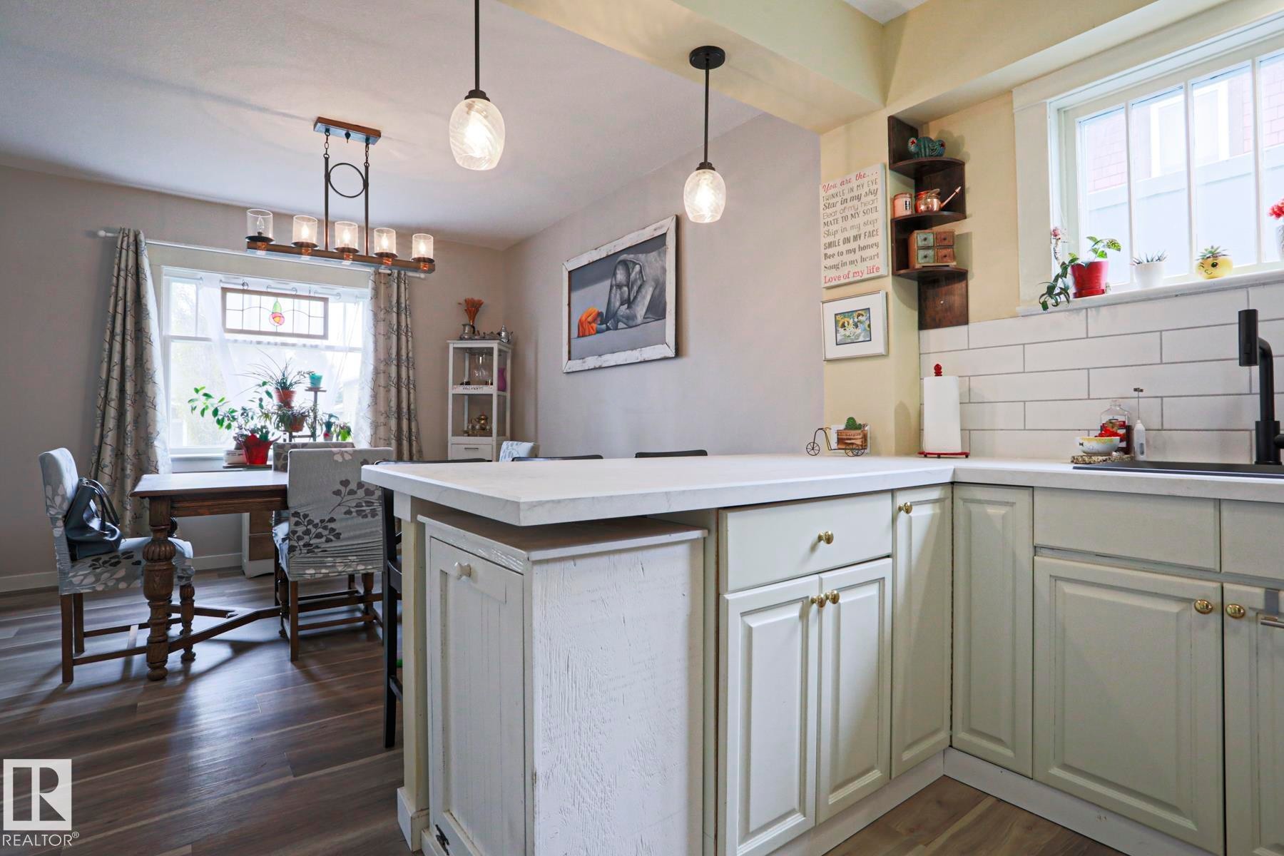 Open-concept kitchen and dining area featuring light-toned cabinetry, white subway tile backsplash, and light countertops - 5113 53 Avenue, Stony Plain, AB - Indoor Photo Showing Kitchen