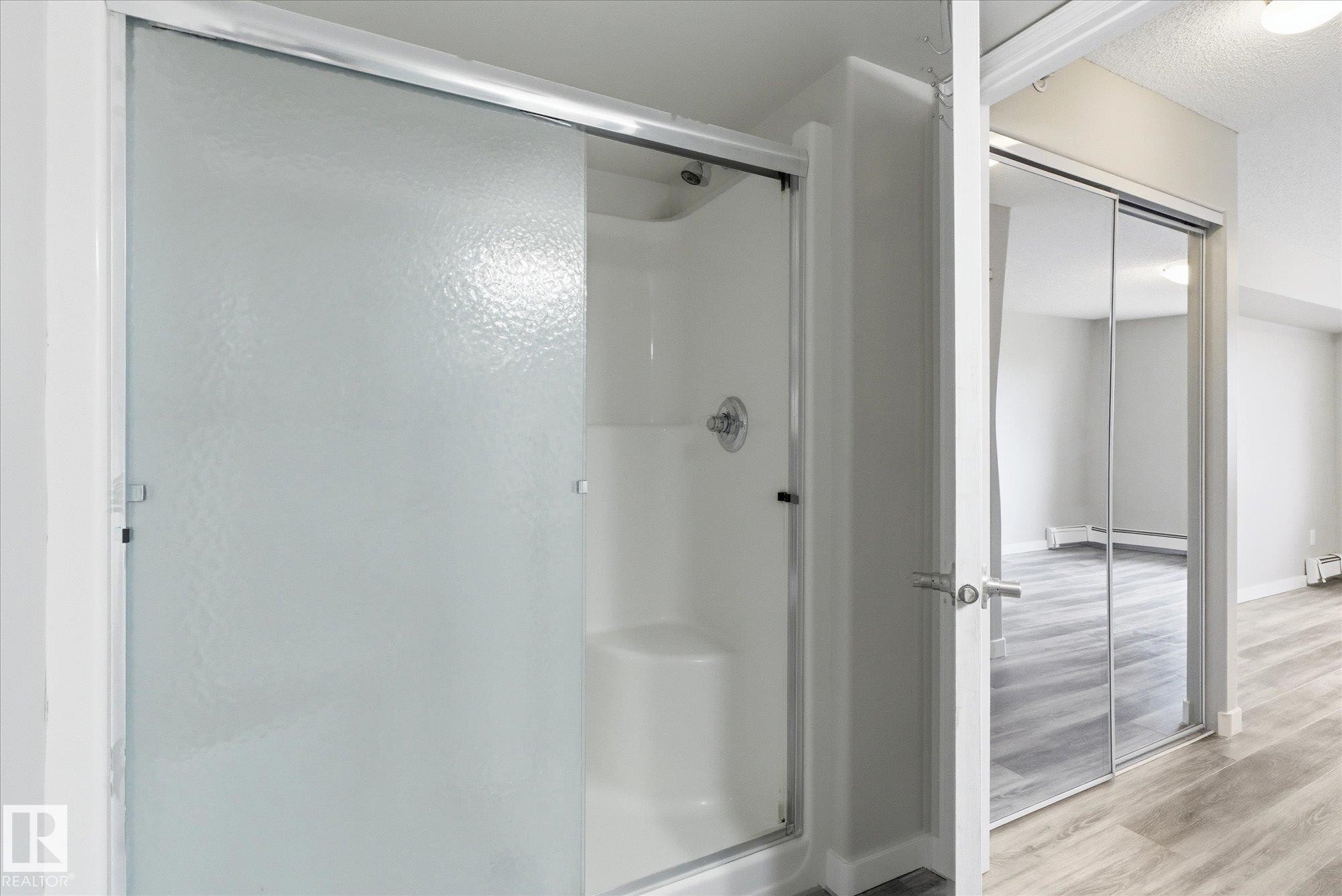 Shower enclosure featuring a sliding textured glass door and chrome hardware - 407 13635 34 Street Nw, Edmonton, AB - Indoor