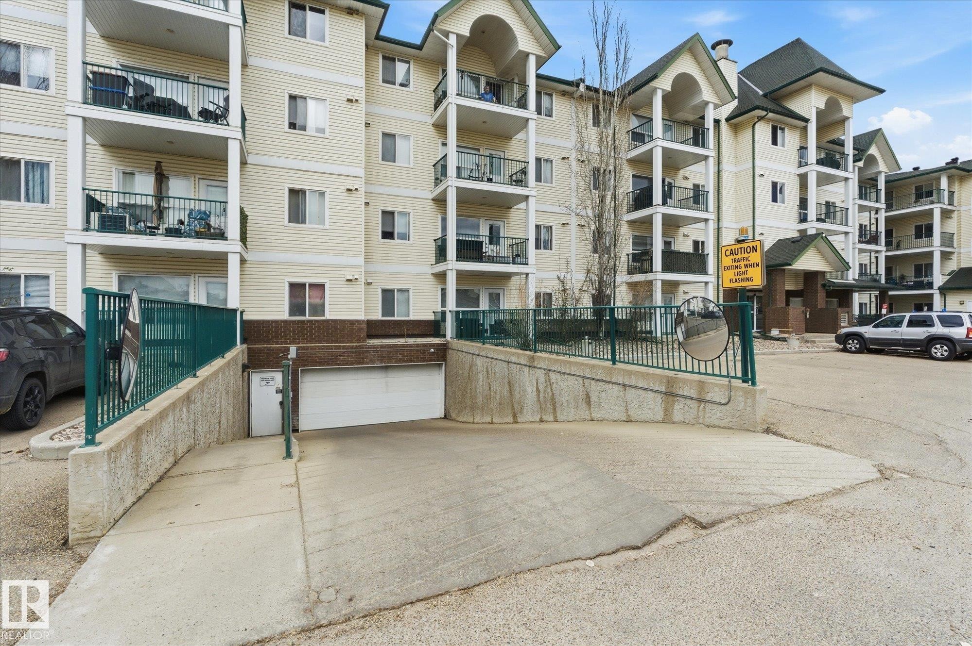 Multi-story residential building featuring light-toned siding and multiple balconies with dark railings - 407 13635 34 Street Nw, Edmonton, AB - Outdoor With Balcony With Facade