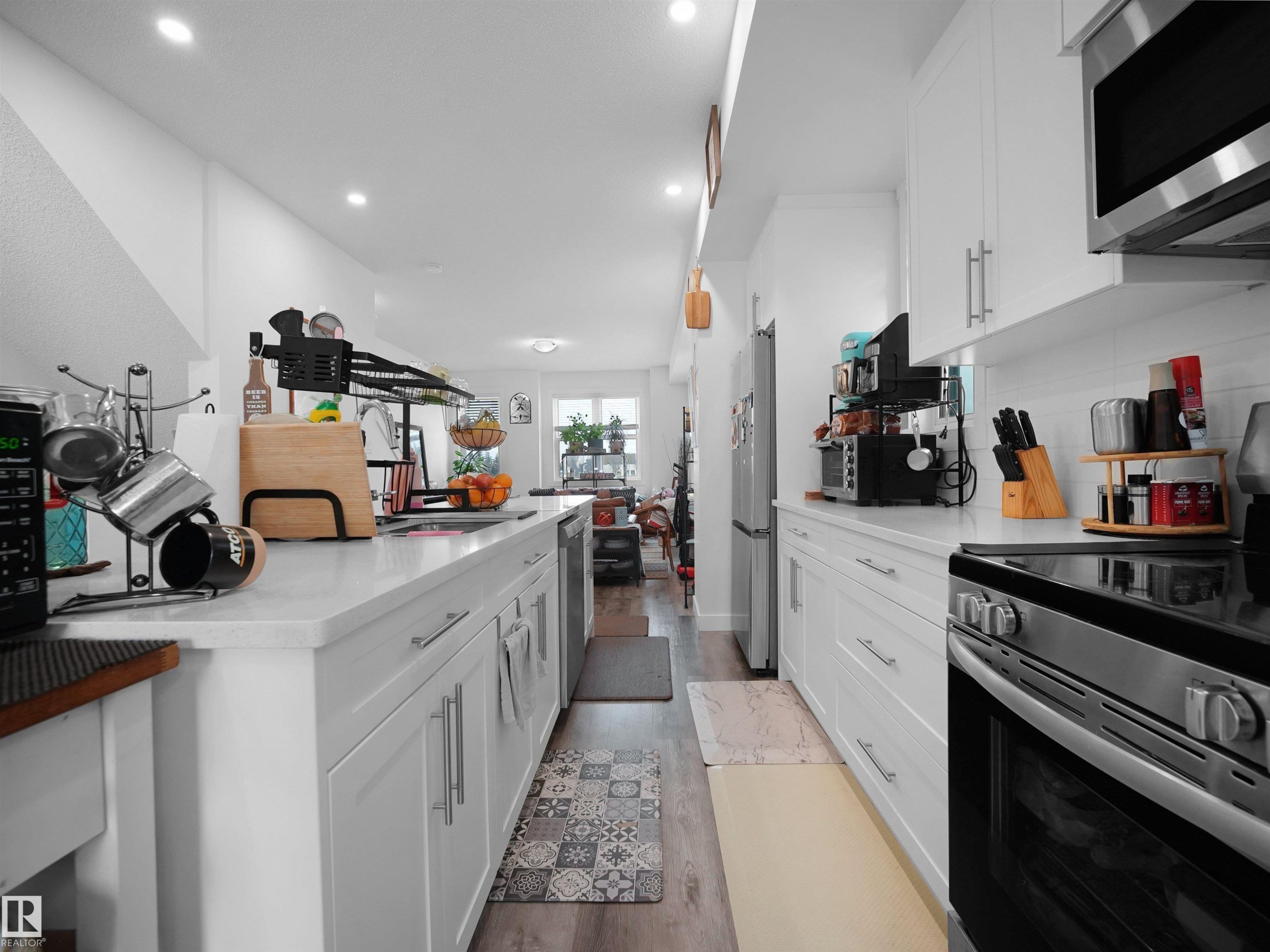 The kitchen features white cabinetry with stainless steel hardware, white countertops, and a stainless steel oven with a black cooktop - 64 655 Watt Boulevard, Edmonton, AB - Indoor Photo Showing Kitchen