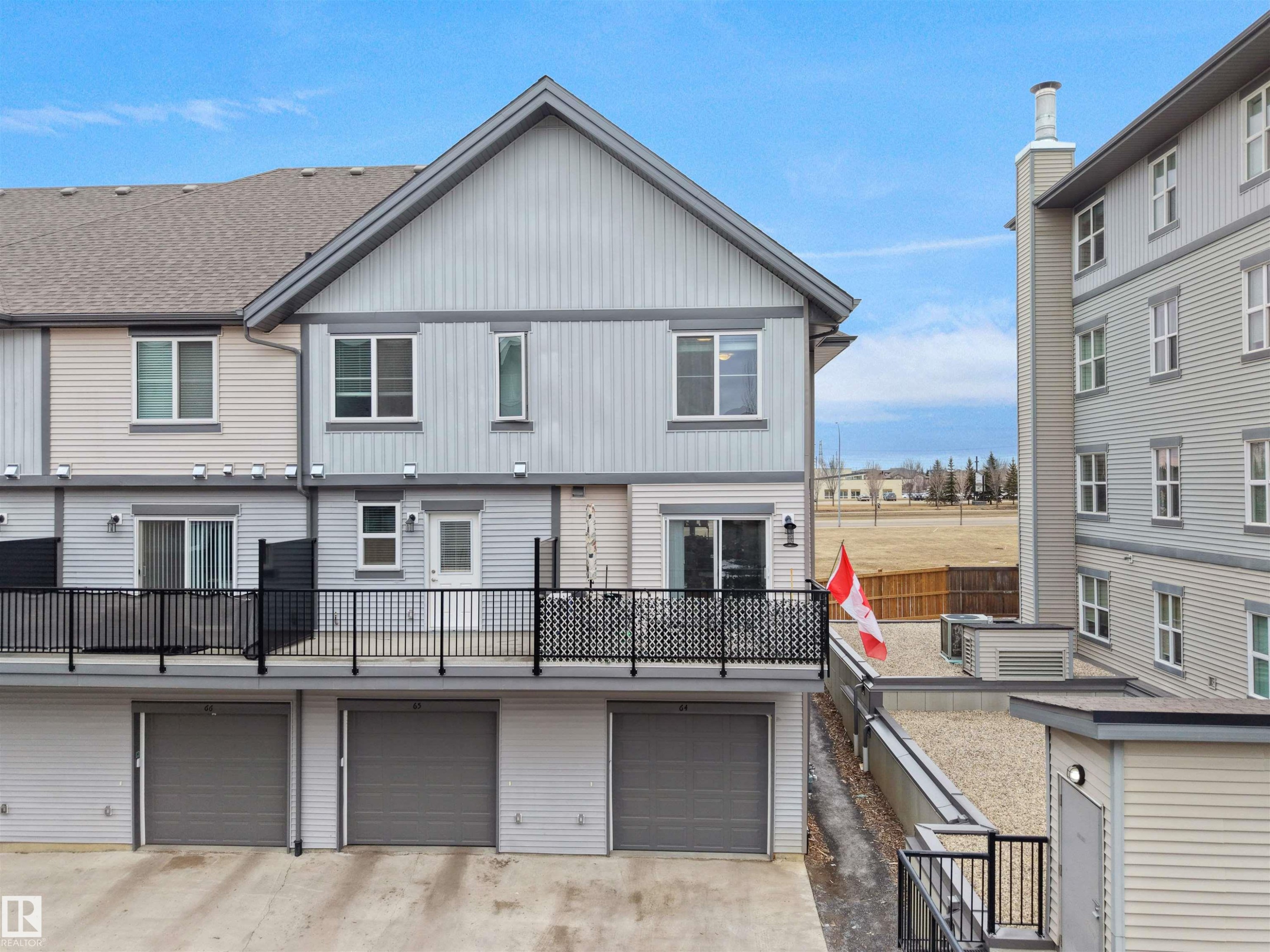 This property features a multi-level design with a light grey exterior siding and a dark grey roof - 64 655 Watt Boulevard, Edmonton, AB - Outdoor