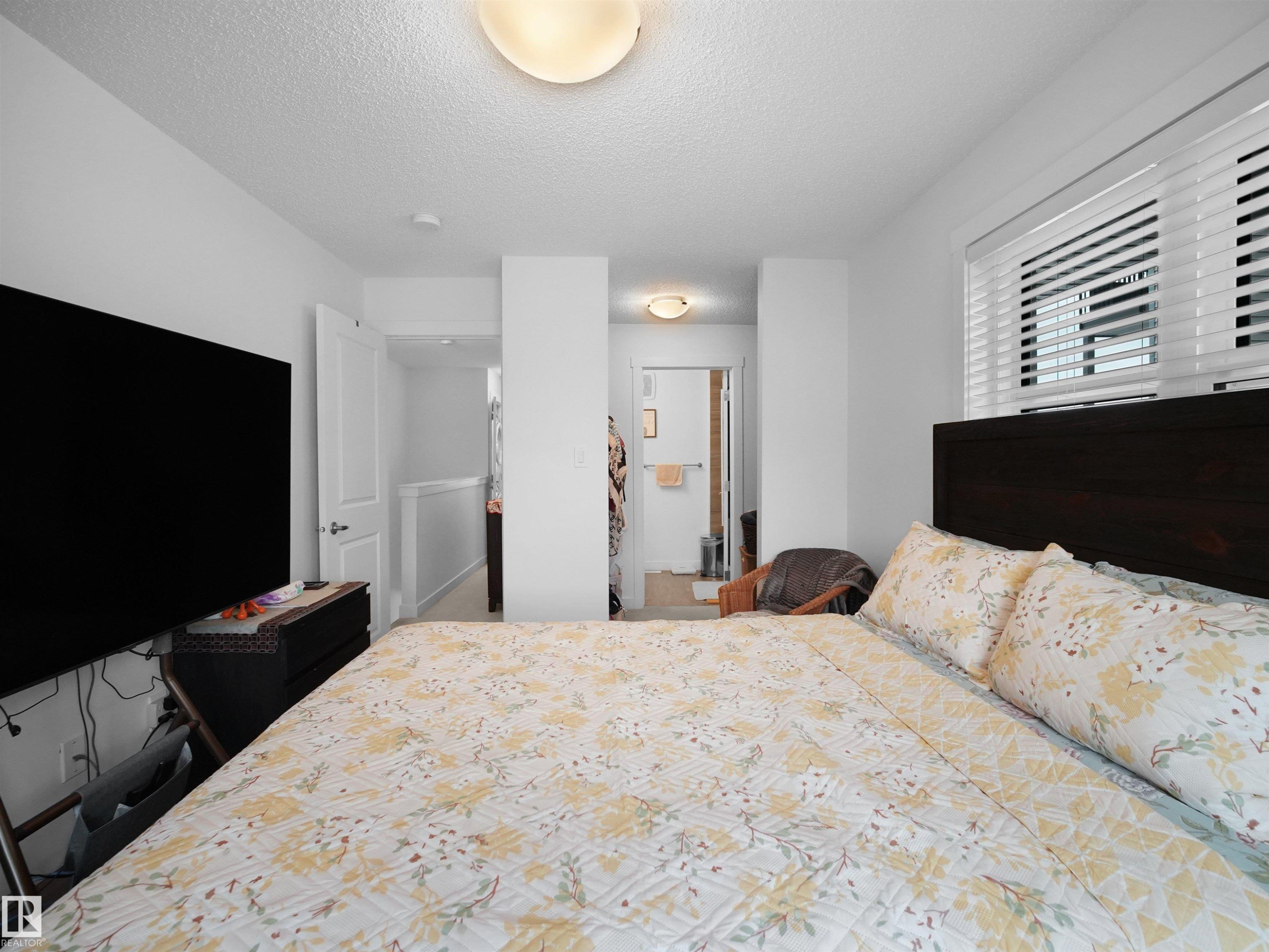 This bedroom features a dark wood headboard, a window with blinds for light control, and an overhead flush mount light fixture - 64 655 Watt Boulevard, Edmonton, AB - Indoor Photo Showing Bedroom