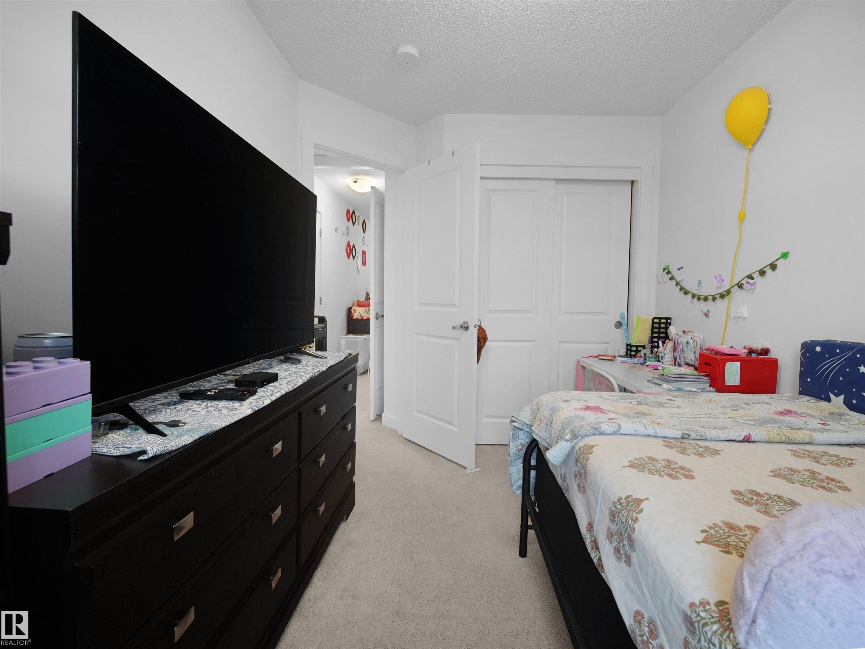 The room features a dark wood dresser and a white door with a dark handle - 64 655 Watt Boulevard, Edmonton, AB - Indoor Photo Showing Bedroom