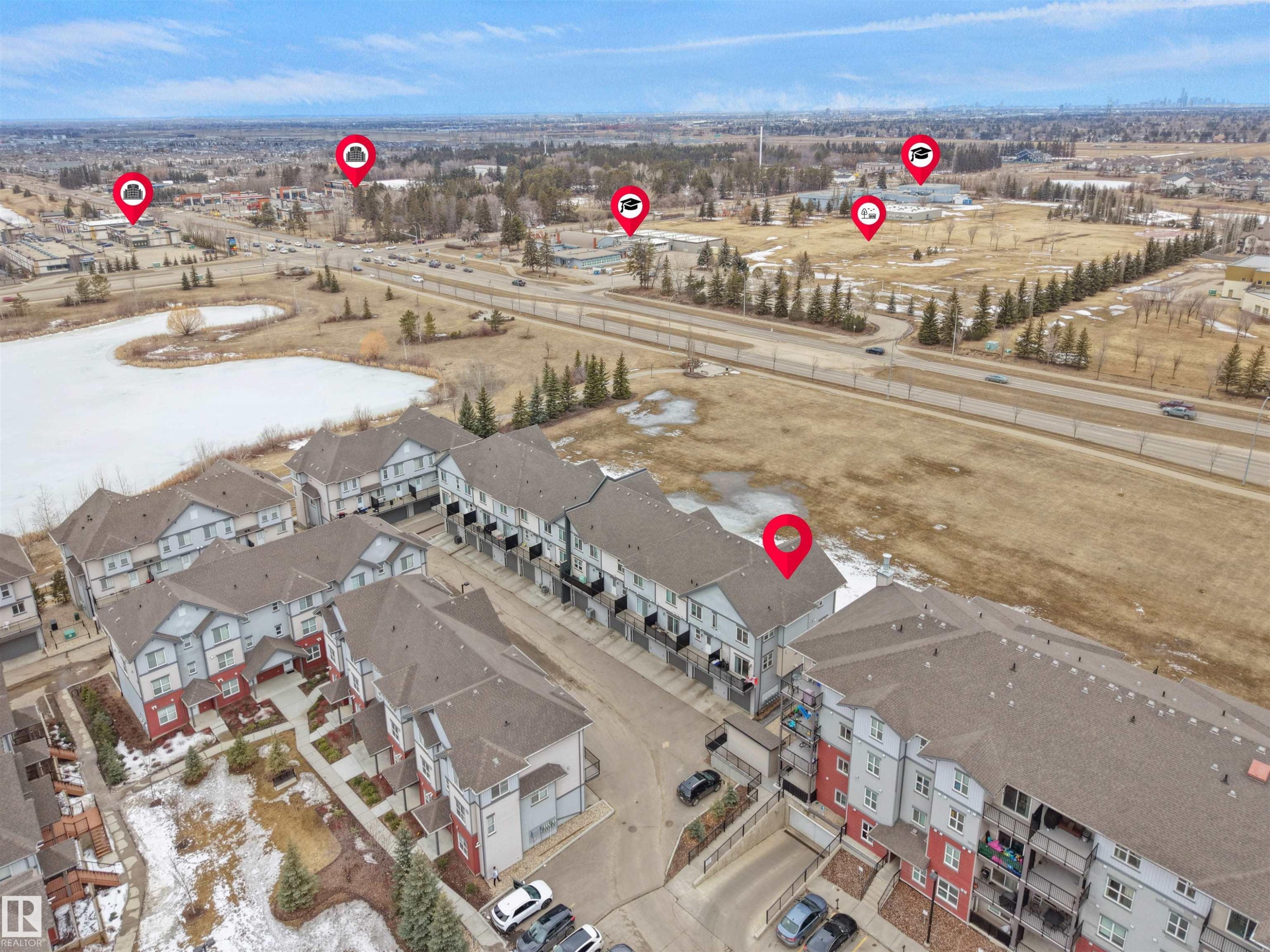 Aerial view showcasing the property within a community of townhouses and apartments, adjacent to a body of water - 64 655 Watt Boulevard, Edmonton, AB - Outdoor With View