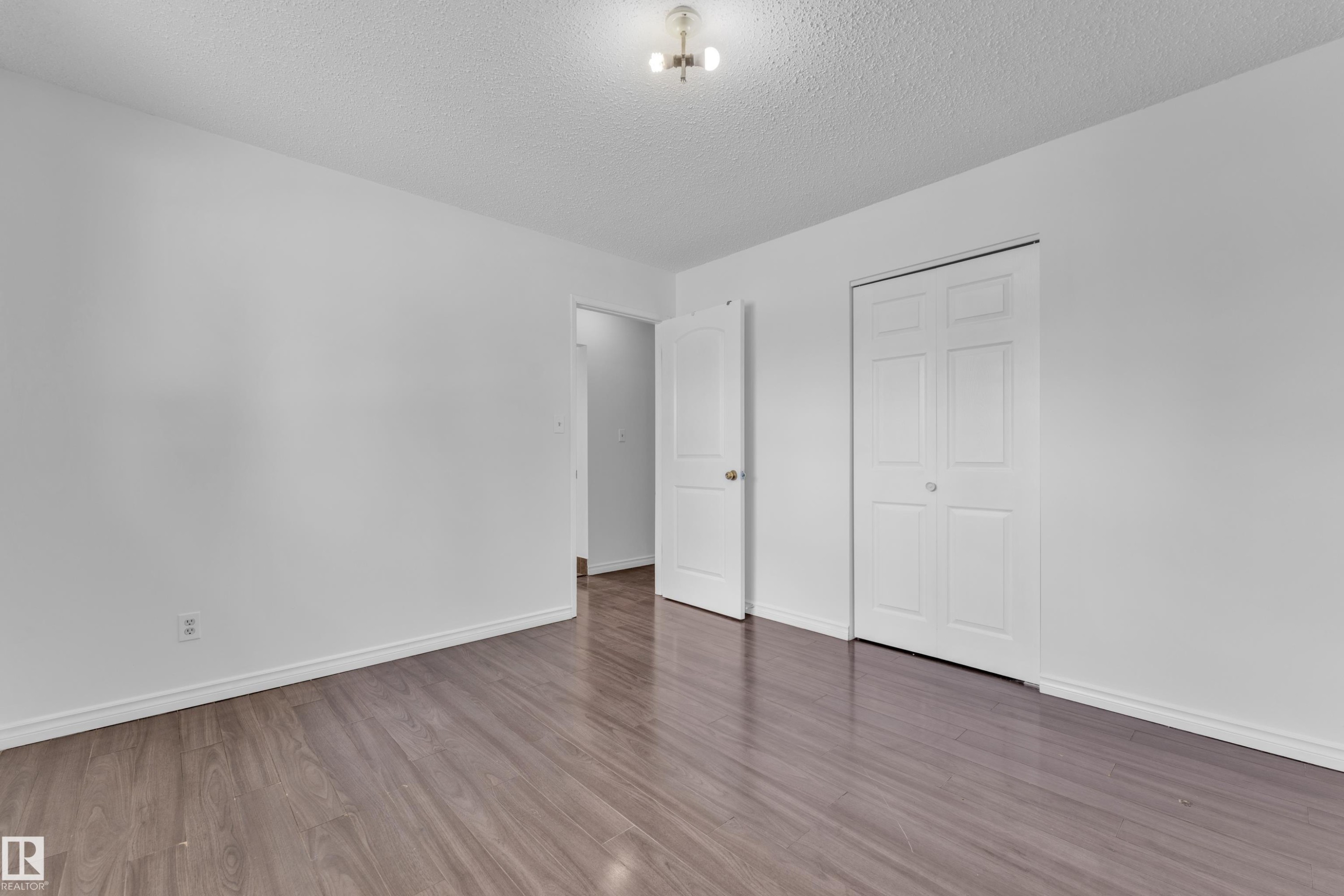 Spacious room featuring wood-finish flooring, white baseboards, and a neutral wall palette - 3520 19 Avenue, Edmonton, AB