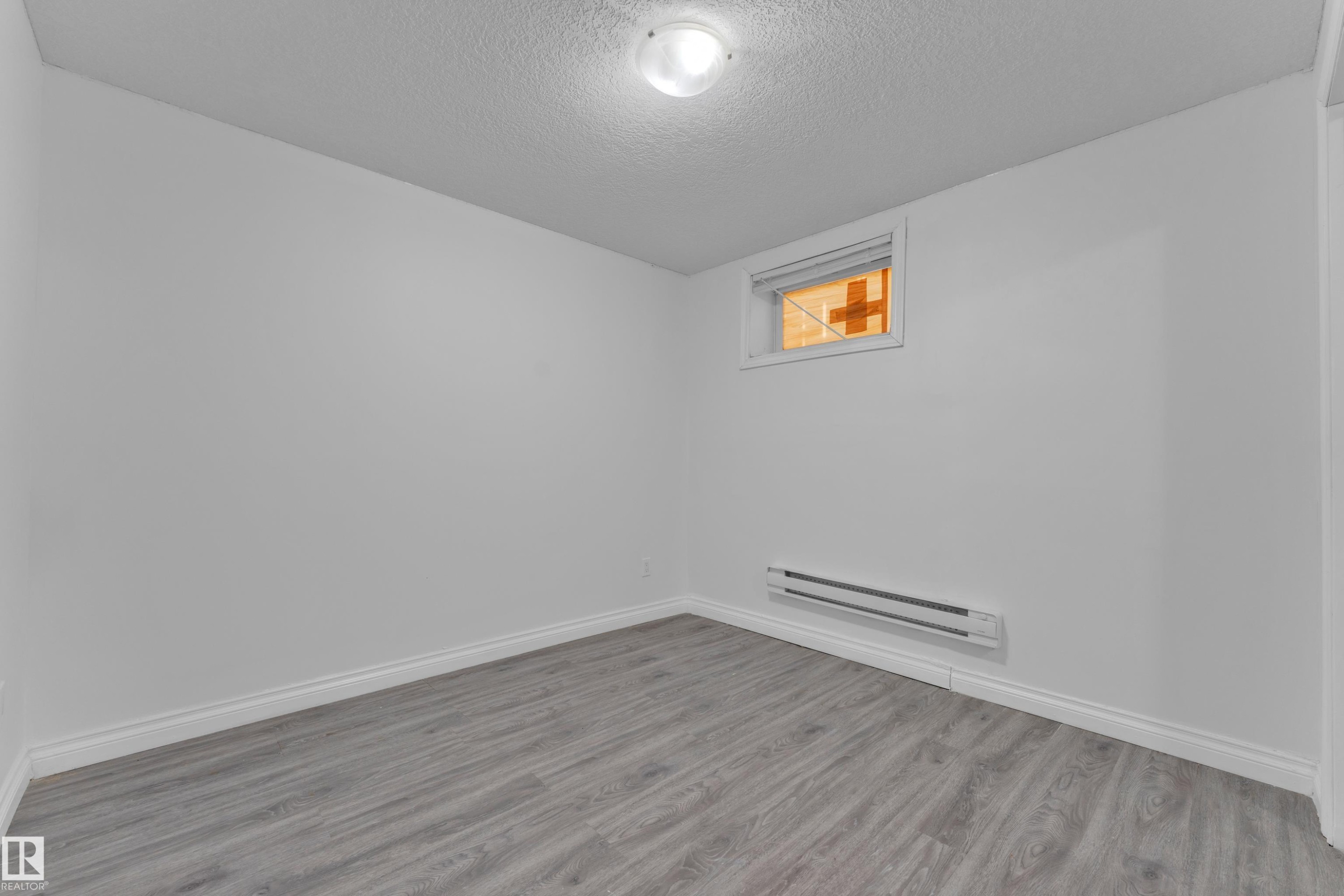 Room featuring wood-finish flooring, white baseboards, and a neutral wall palette - 3520 19 Avenue, Edmonton, AB