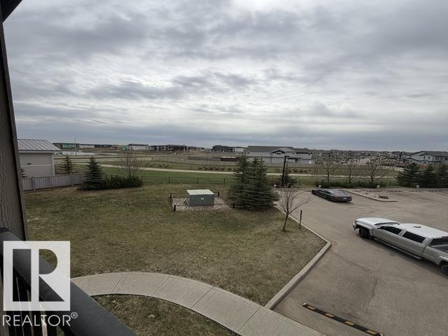 Expansive outdoor space featuring a paved parking area and grass lawn - 321 107 Watt Common, Edmonton, AB - Outdoor With View