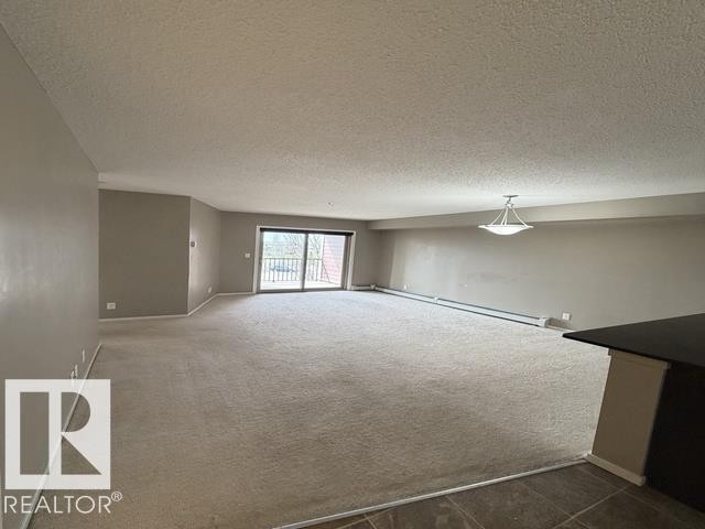 Spacious living area featuring neutral carpeting and light gray wall tones - 321 107 Watt Common, Edmonton, AB - Indoor Photo Showing Other Room