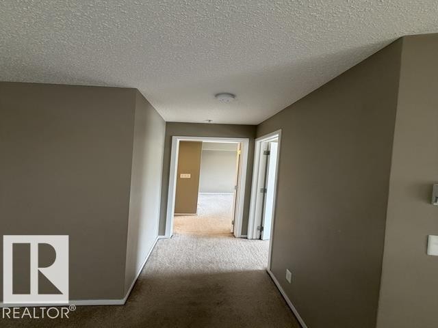 Hallway with carpet flooring, neutral tone wall paint, white trim, and overhead lighting - 321 107 Watt Common, Edmonton, AB - Indoor Photo Showing Other Room