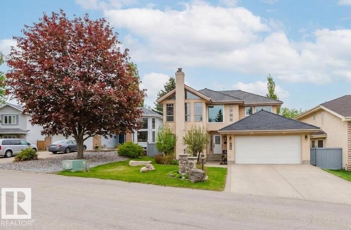 Stucco exterior with a two-car garage, pitched shingle roof, mature front yard tree, and a concrete driveway - 342 O'Connor Close, Edmonton, AB - Outdoor With Facade