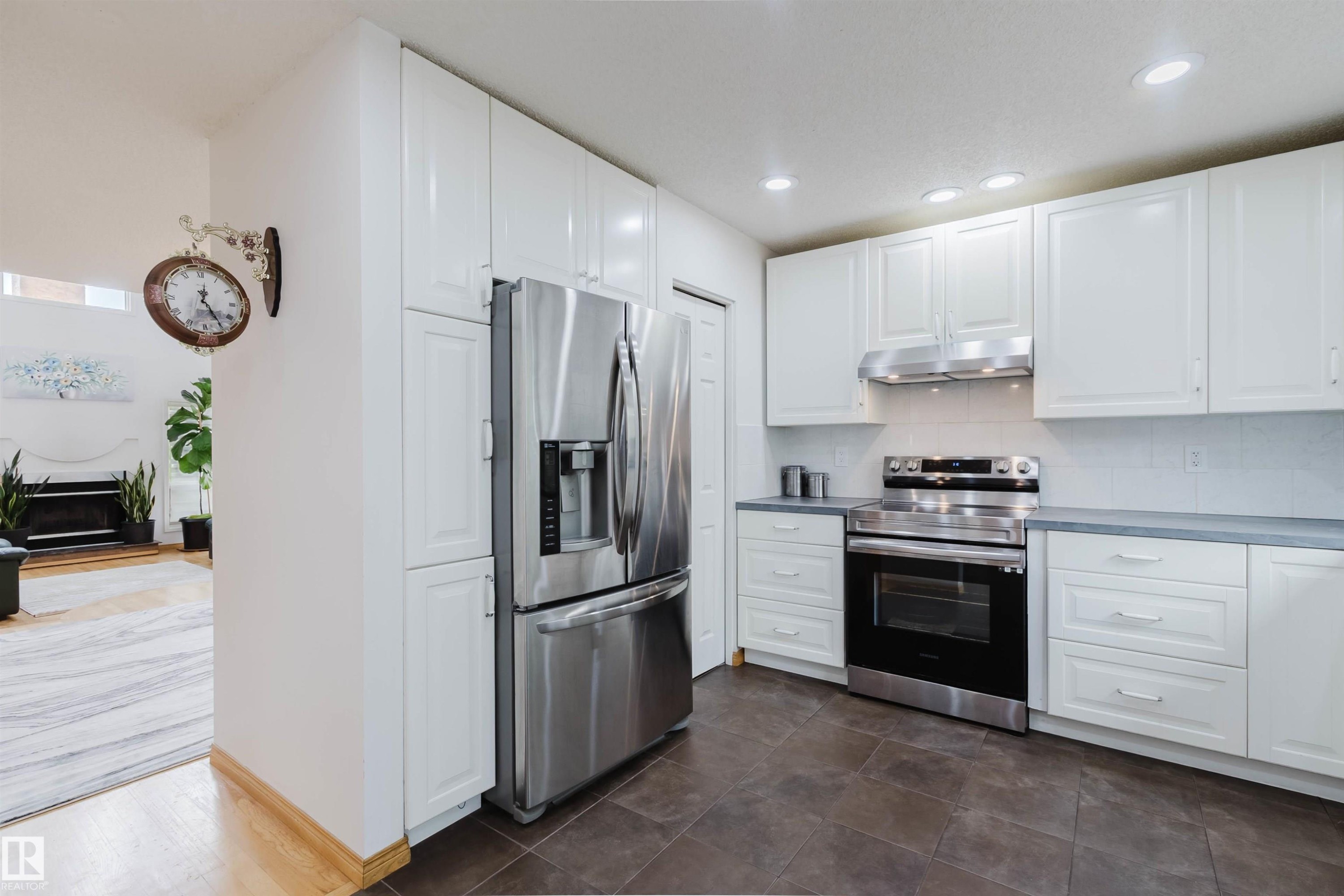 Modern kitchen featuring white cabinetry, stainless steel appliances, dark tile flooring, light countertops, and recessed lighting - 342 O'Connor Close, Edmonton, AB - Indoor Photo Showing Kitchen