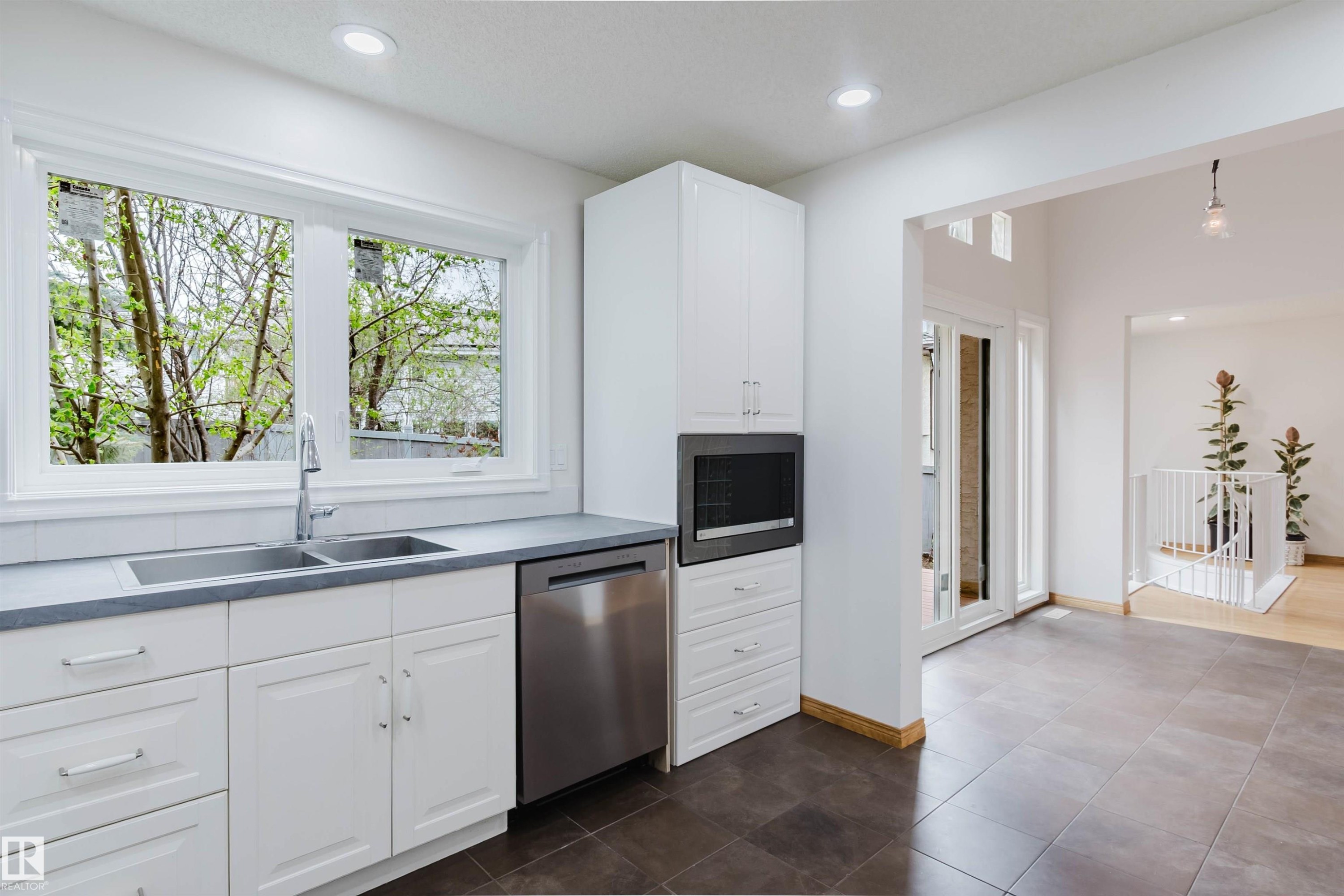 Kitchen featuring white shaker-style cabinetry, a stainless steel double sink with a gooseneck faucet, a built-in stainless steel dishwasher, and a built-in microwave - 342 O'Connor Close, Edmonton, AB - Indoor Photo Showing Kitchen With Double Sink
