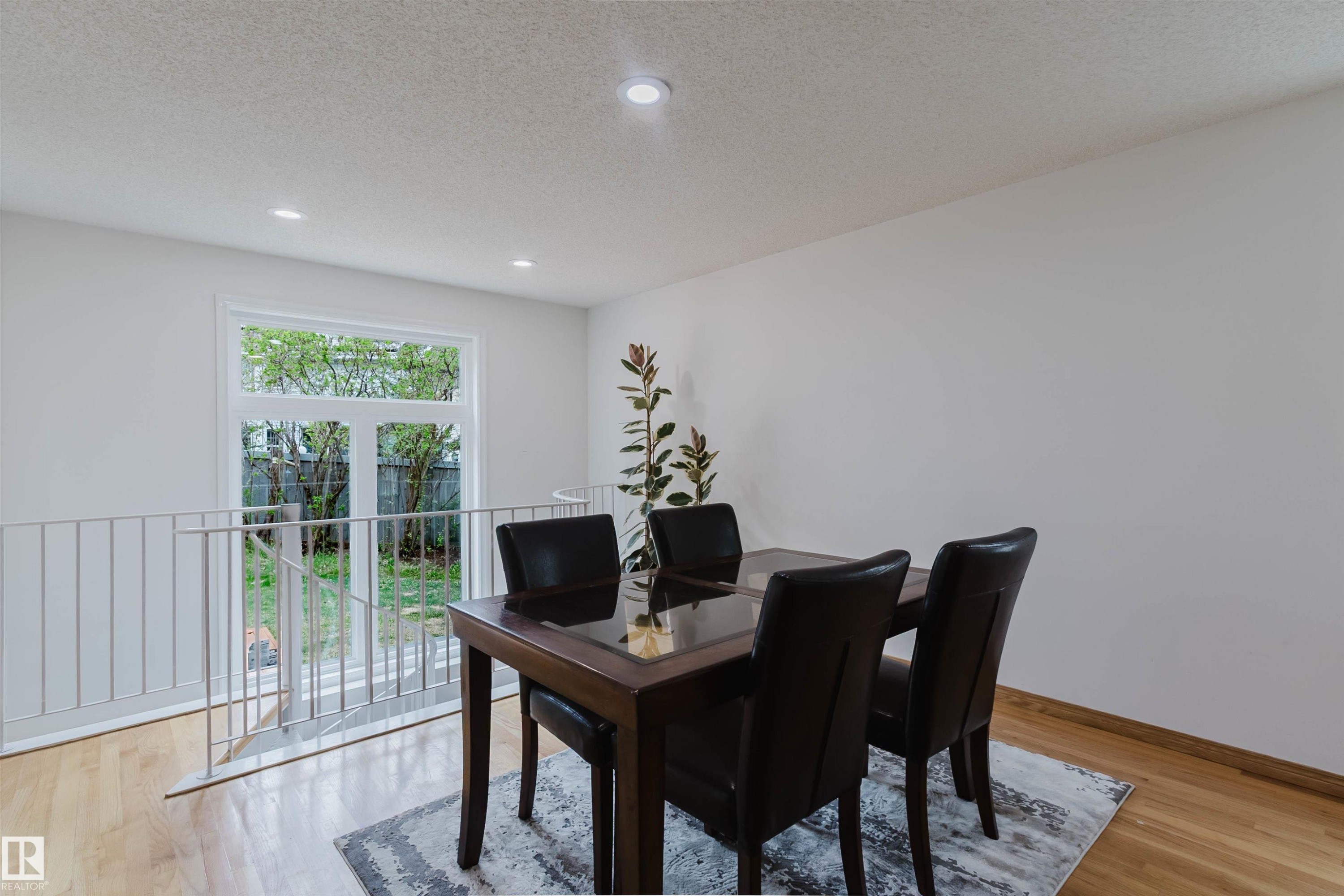 Bright dining area featuring light wood-finish flooring, recessed lighting, and a white railing overlooking a lower level - 342 O'Connor Close, Edmonton, AB - Indoor