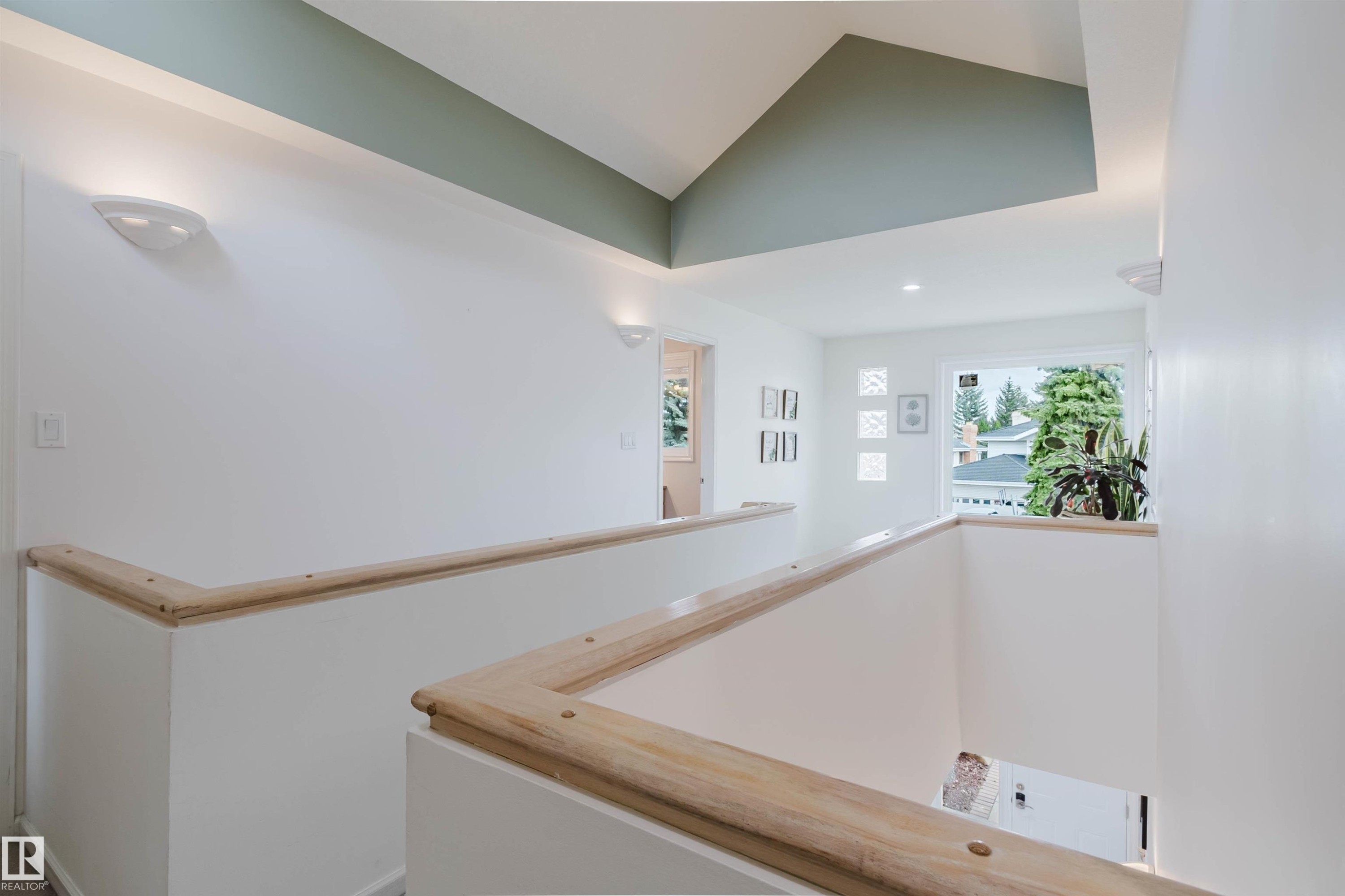 Upper-level hallway featuring a vaulted ceiling with accent paint, natural wood handrails, recessed lighting, wall sconces, and a large window - 342 O'Connor Close, Edmonton, AB - Indoor Photo Showing Other Room