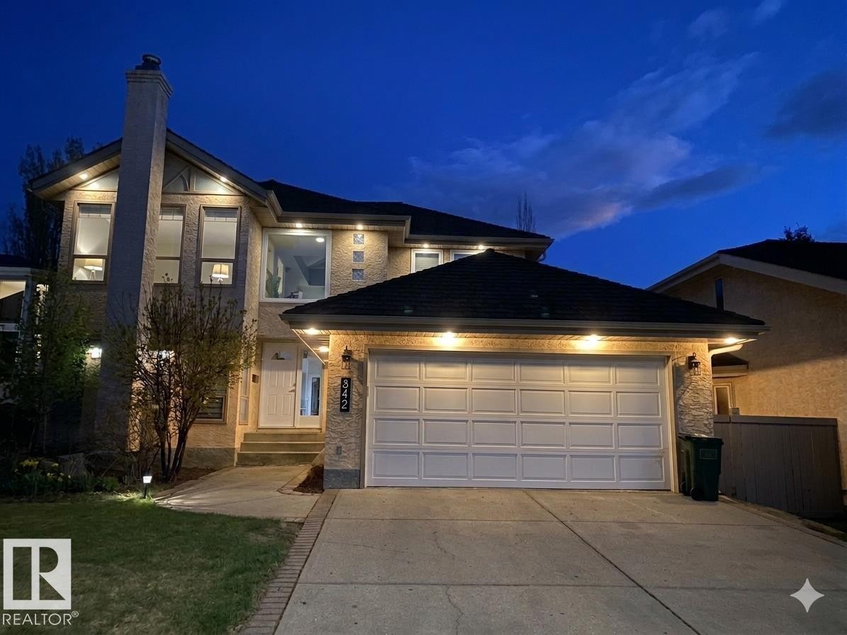 Stucco exterior with stone accents, featuring a large two-car garage, prominent chimney, and a multi-pane glass entry door - 342 O'Connor Close, Edmonton, AB - Outdoor