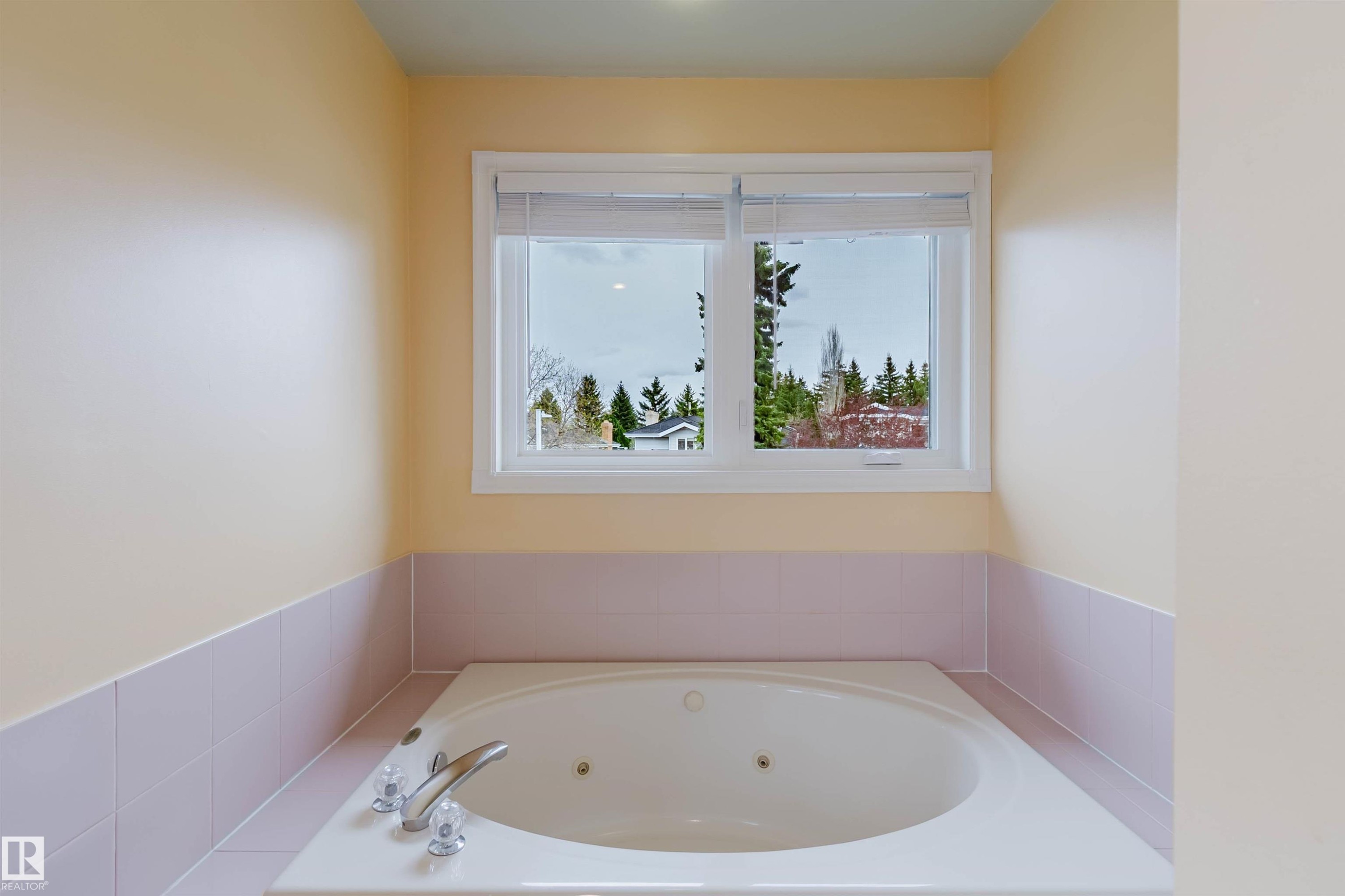 Built-in jetted tub with chrome fixtures, tiled surround, and upper wall in a light neutral tone - 342 O'Connor Close, Edmonton, AB - Indoor Photo Showing Bathroom