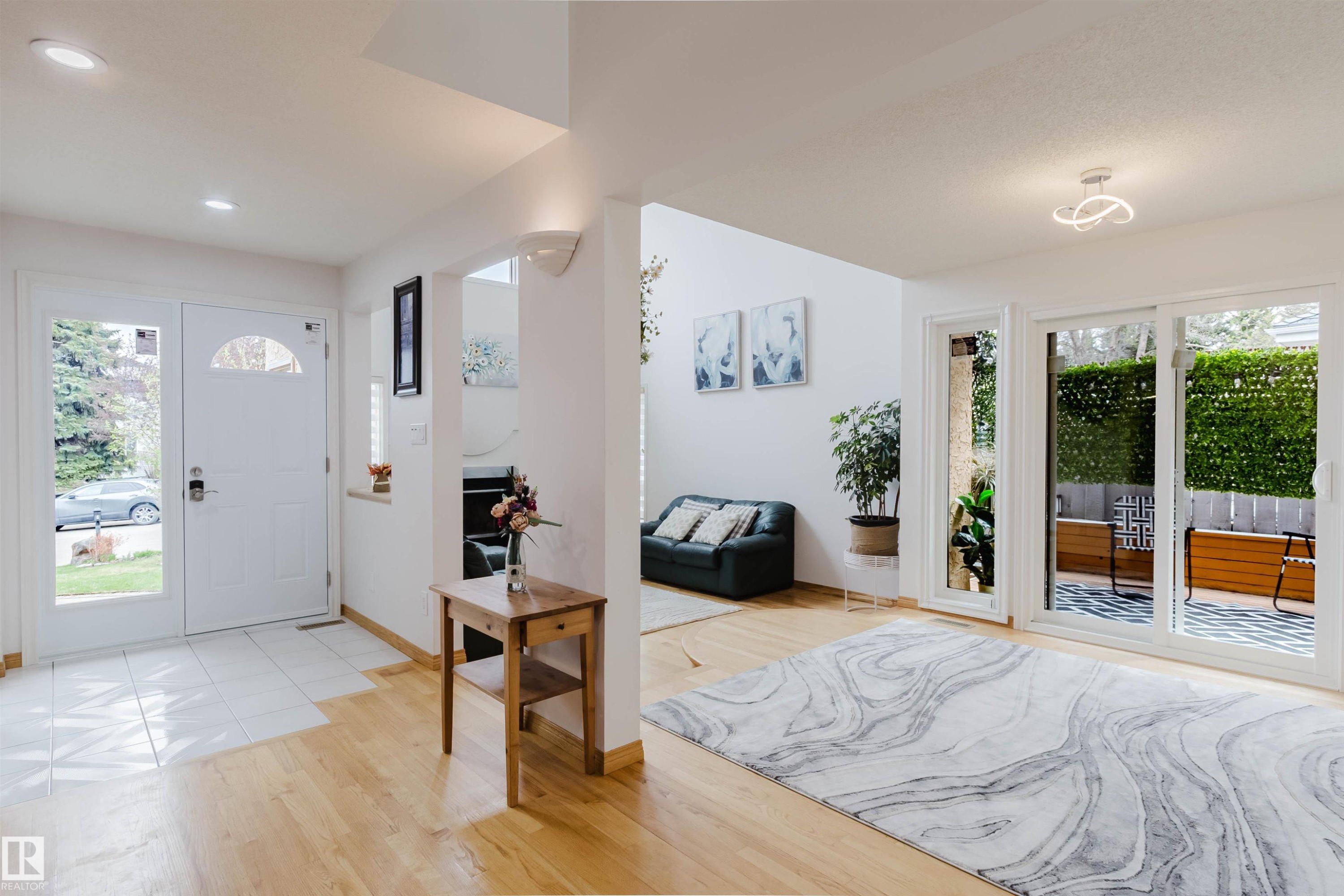 Entryway with light wood-finish flooring and white tile, featuring a white front door with an arched transom window and a full-light sidelight - 342 O'Connor Close, Edmonton, AB - Indoor Photo Showing Other Room