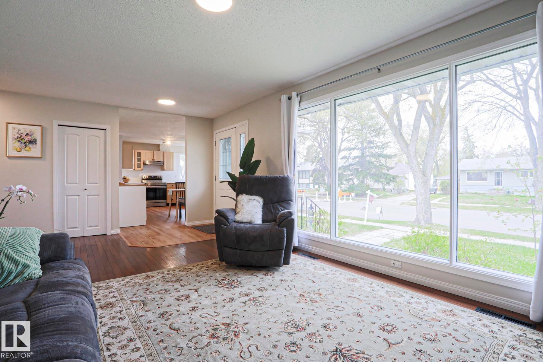 Expansive living space featuring a large picture window, wood-finish flooring, and recessed lighting - 9523 151 Street, Edmonton, AB - Indoor Photo Showing Living Room