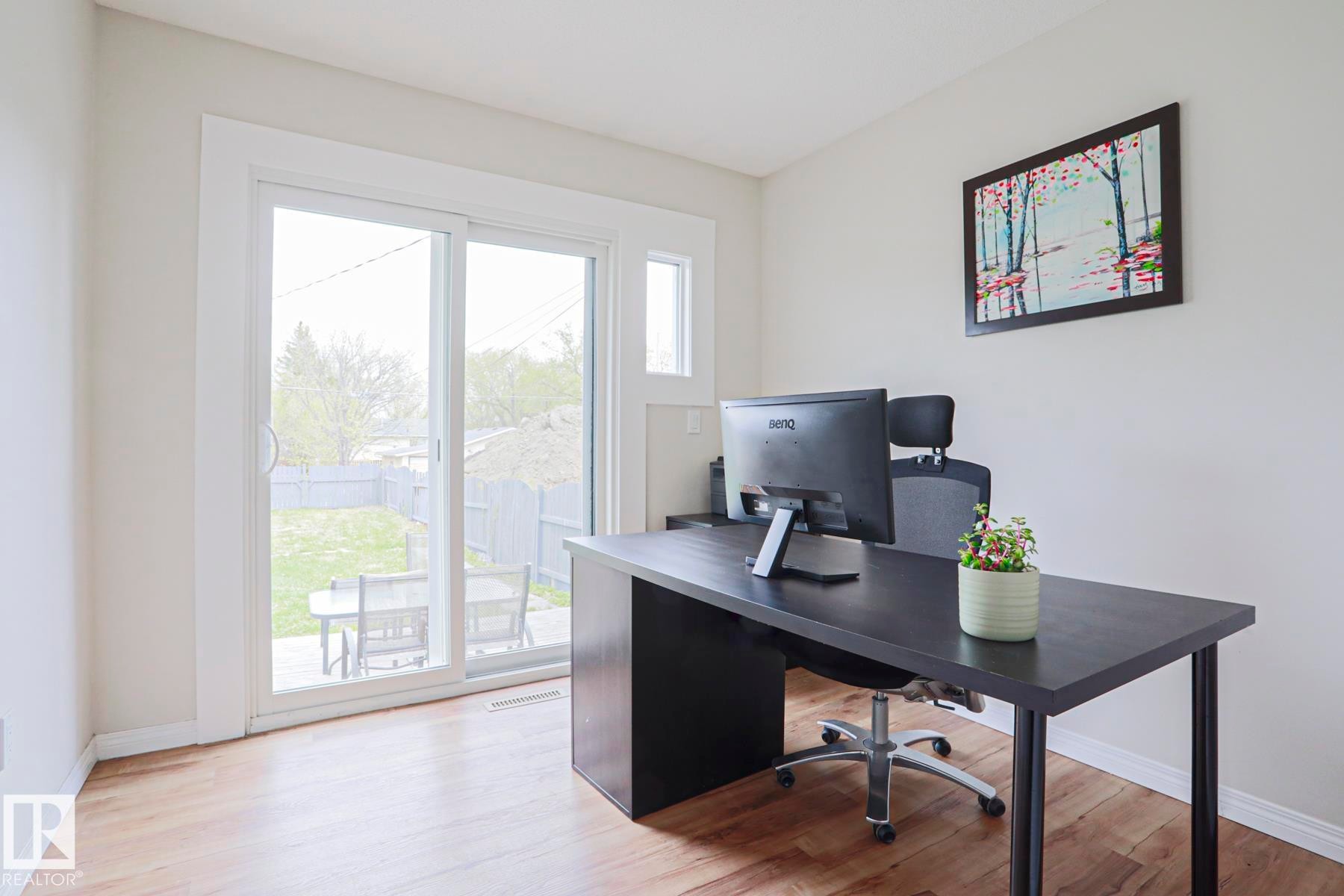 Bright interior space featuring wood-finish flooring and a sliding glass door providing direct outdoor access to a fenced yard - 9523 151 Street, Edmonton, AB - Indoor Photo Showing Office