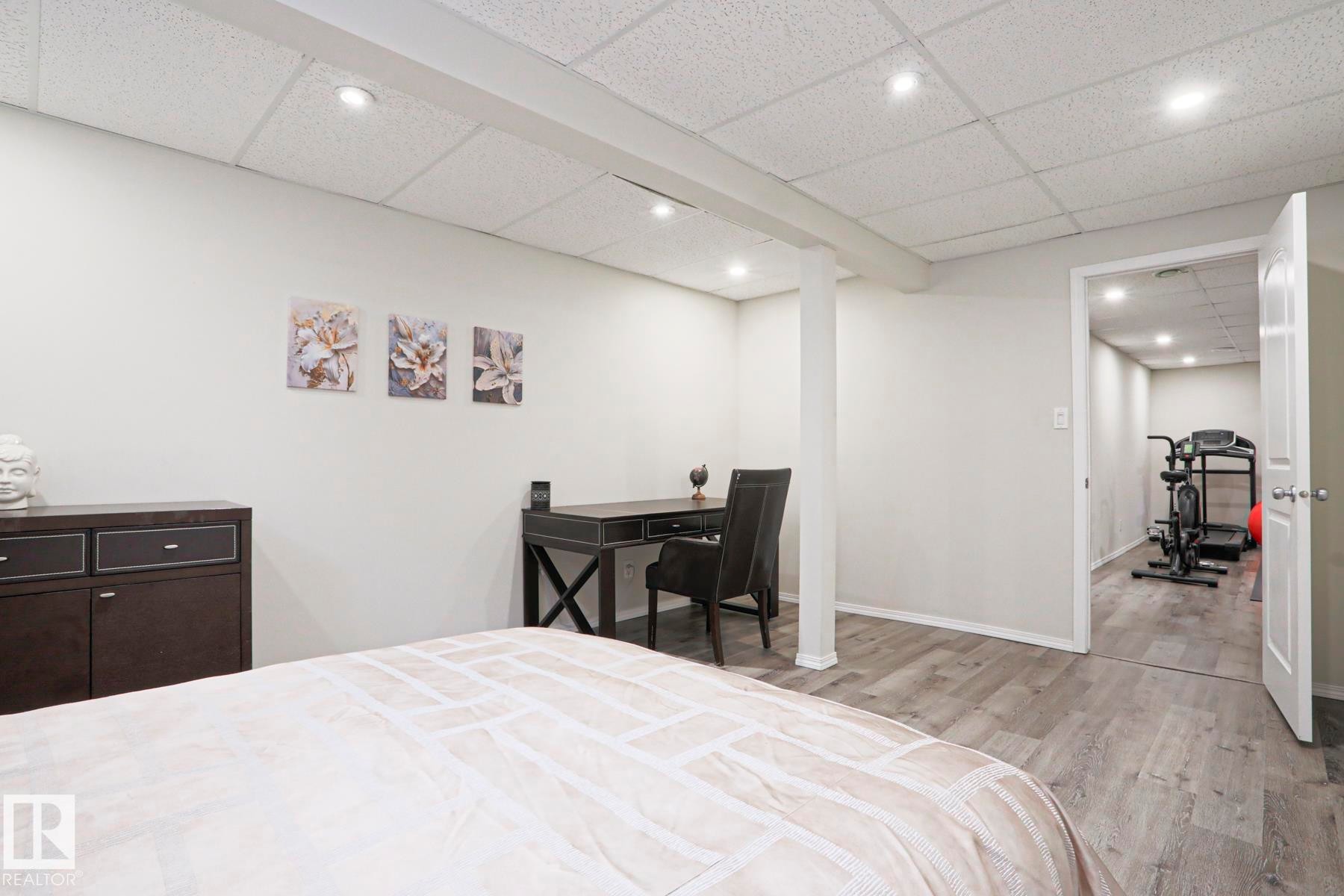Finished lower level featuring recessed lighting, light gray walls, wood-finish flooring, and an open doorway to an additional room - 9523 151 Street, Edmonton, AB - Indoor Photo Showing Bedroom