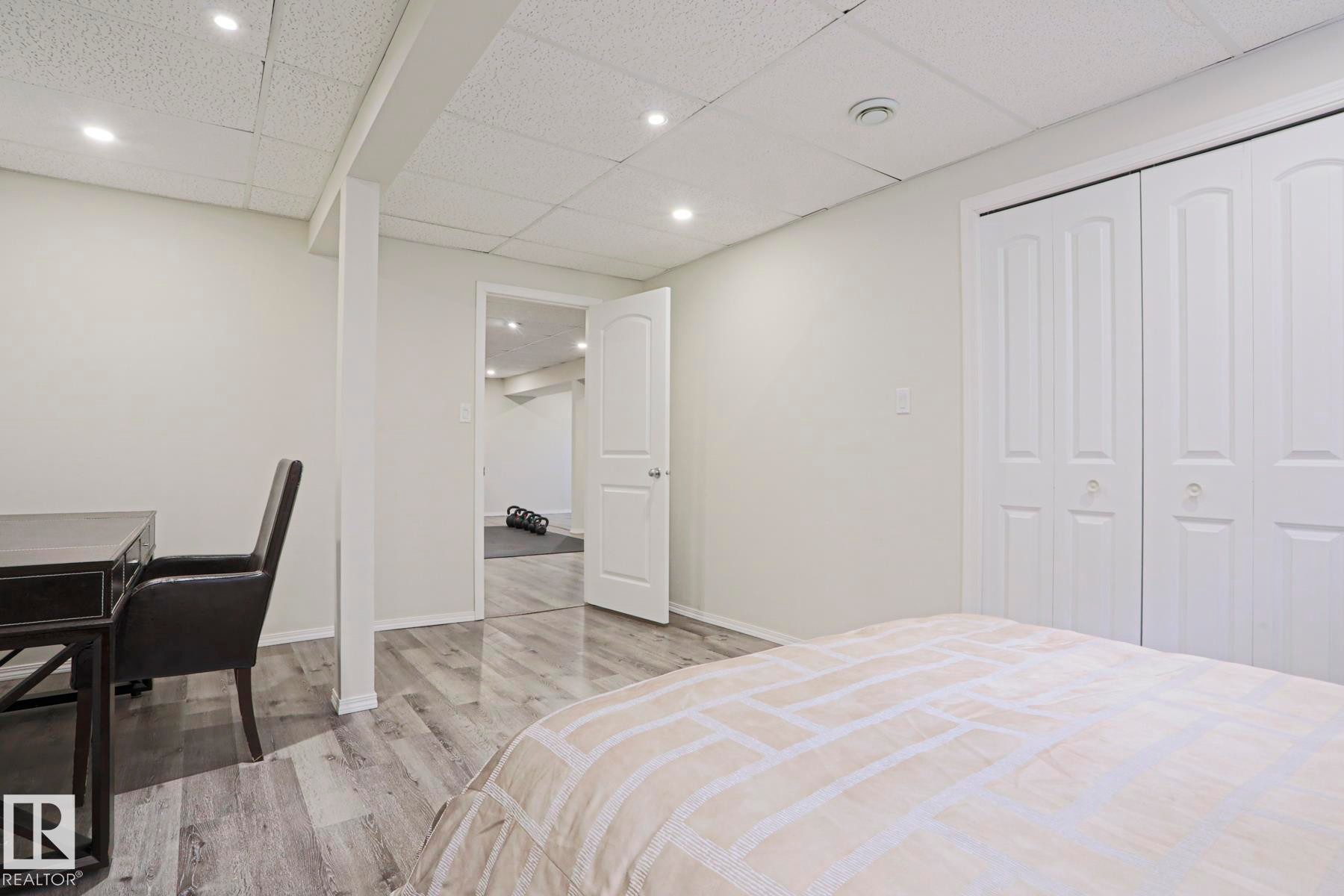 White interior room featuring gray wood-finish flooring, recessed ceiling lighting, and a white bi-fold closet - 9523 151 Street, Edmonton, AB - Indoor Photo Showing Bedroom