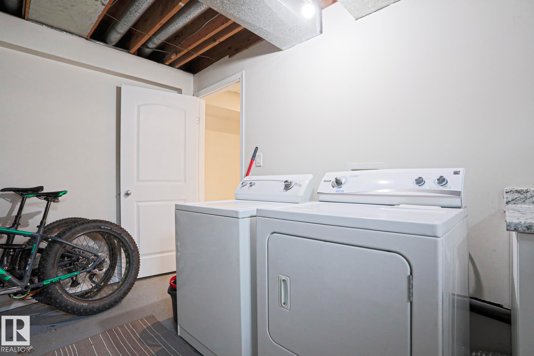 Dedicated laundry area featuring a white washer and dryer set, white walls, and a visible wood-beamed ceiling - 9523 151 Street, Edmonton, AB - Indoor Photo Showing Laundry Room