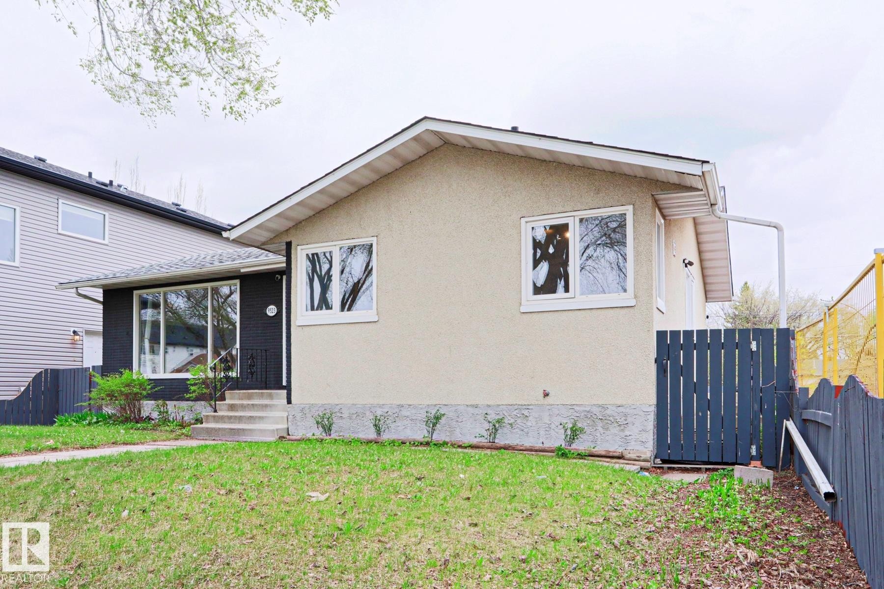 Ranch-style exterior featuring a stucco facade, dark accent siding, and white-framed windows - 9523 151 Street, Edmonton, AB - Outdoor