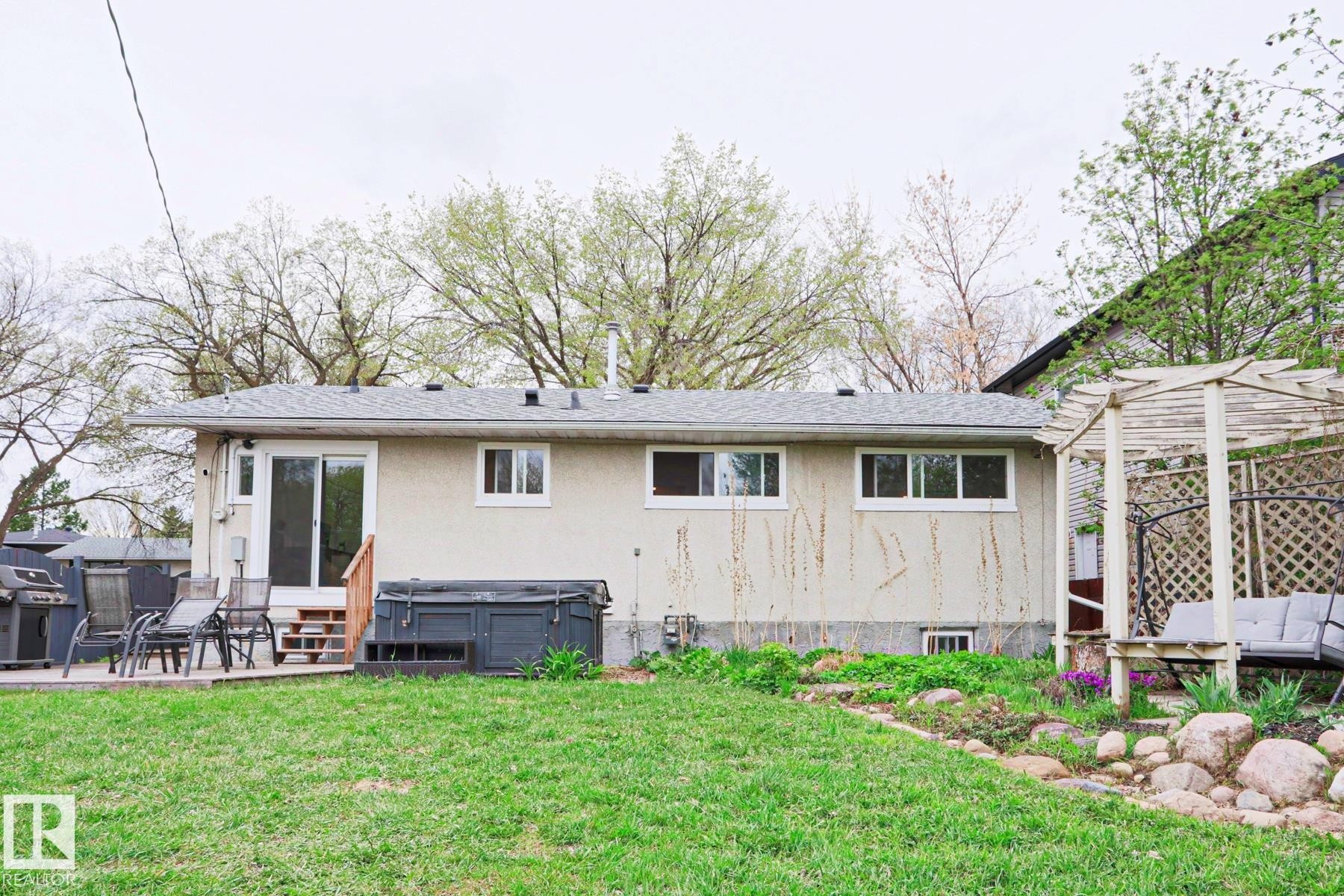 Rear exterior featuring a sliding glass door, wooden deck, and a stucco finish - 9523 151 Street, Edmonton, AB - Outdoor With Deck Patio Veranda