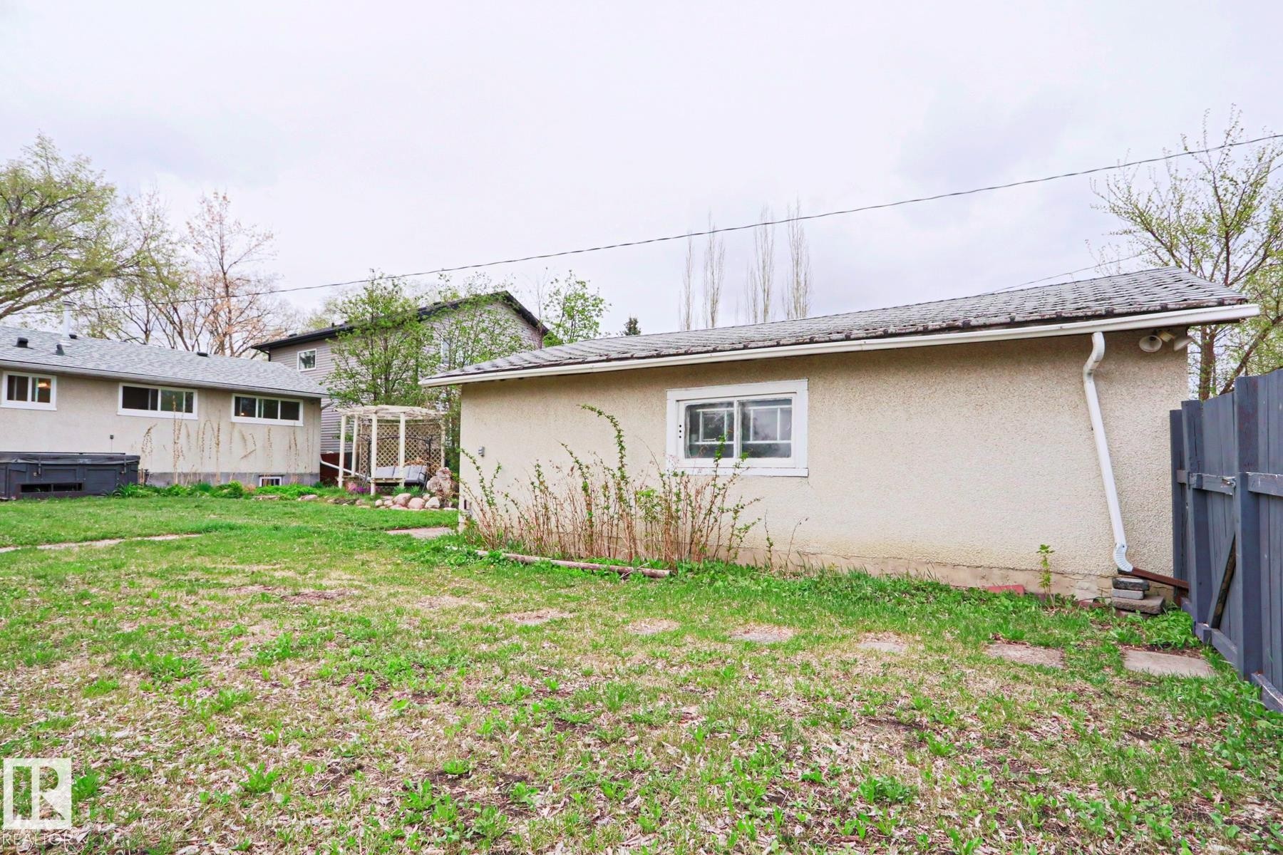 Detached structure with stucco exterior, a shingled roof, and a visible window, situated on a grassy lot - 9523 151 Street, Edmonton, AB - Outdoor