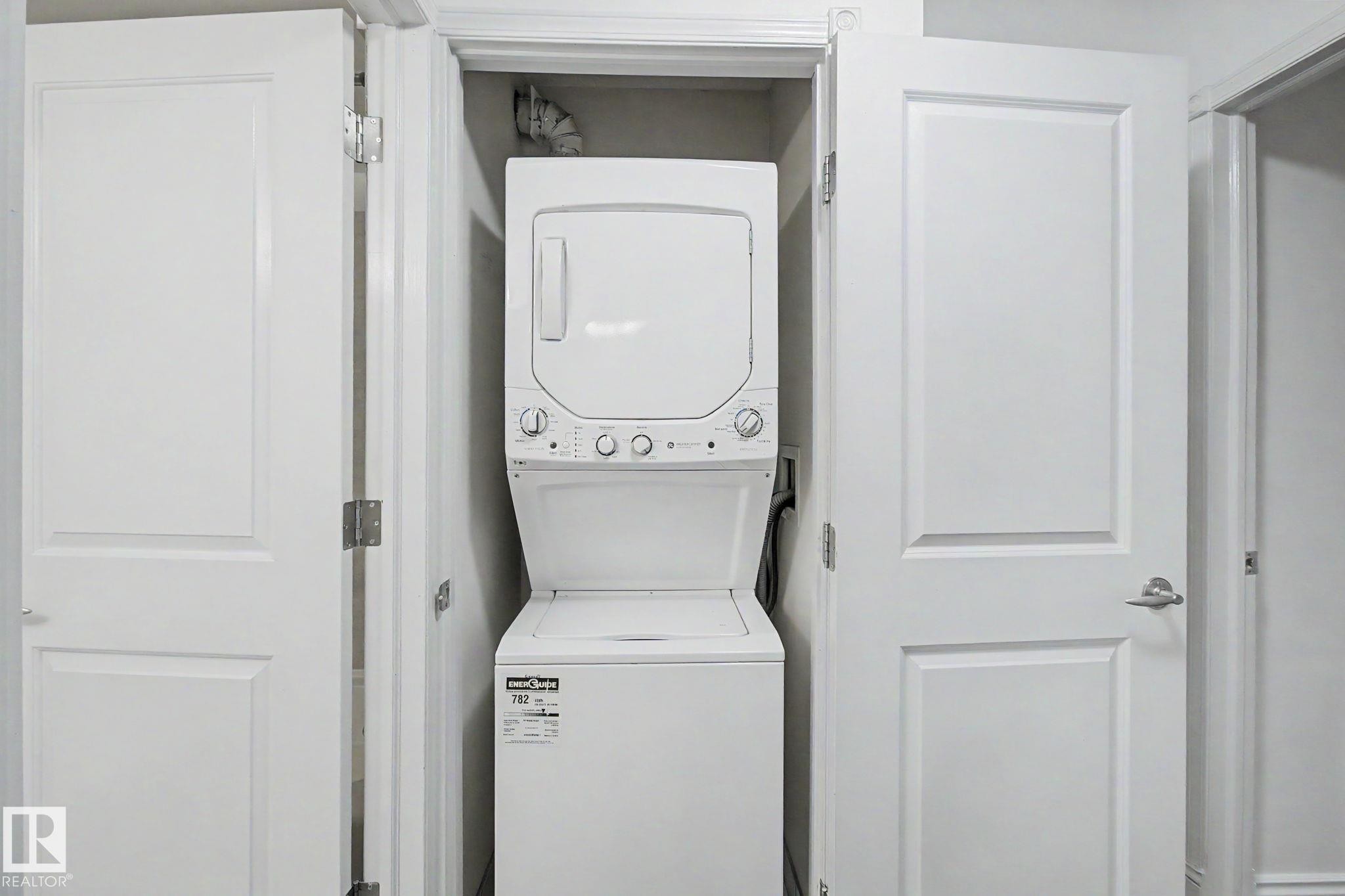Dedicated laundry closet featuring a stackable washer and dryer unit - 213 17404 64 Avenue, Edmonton, AB