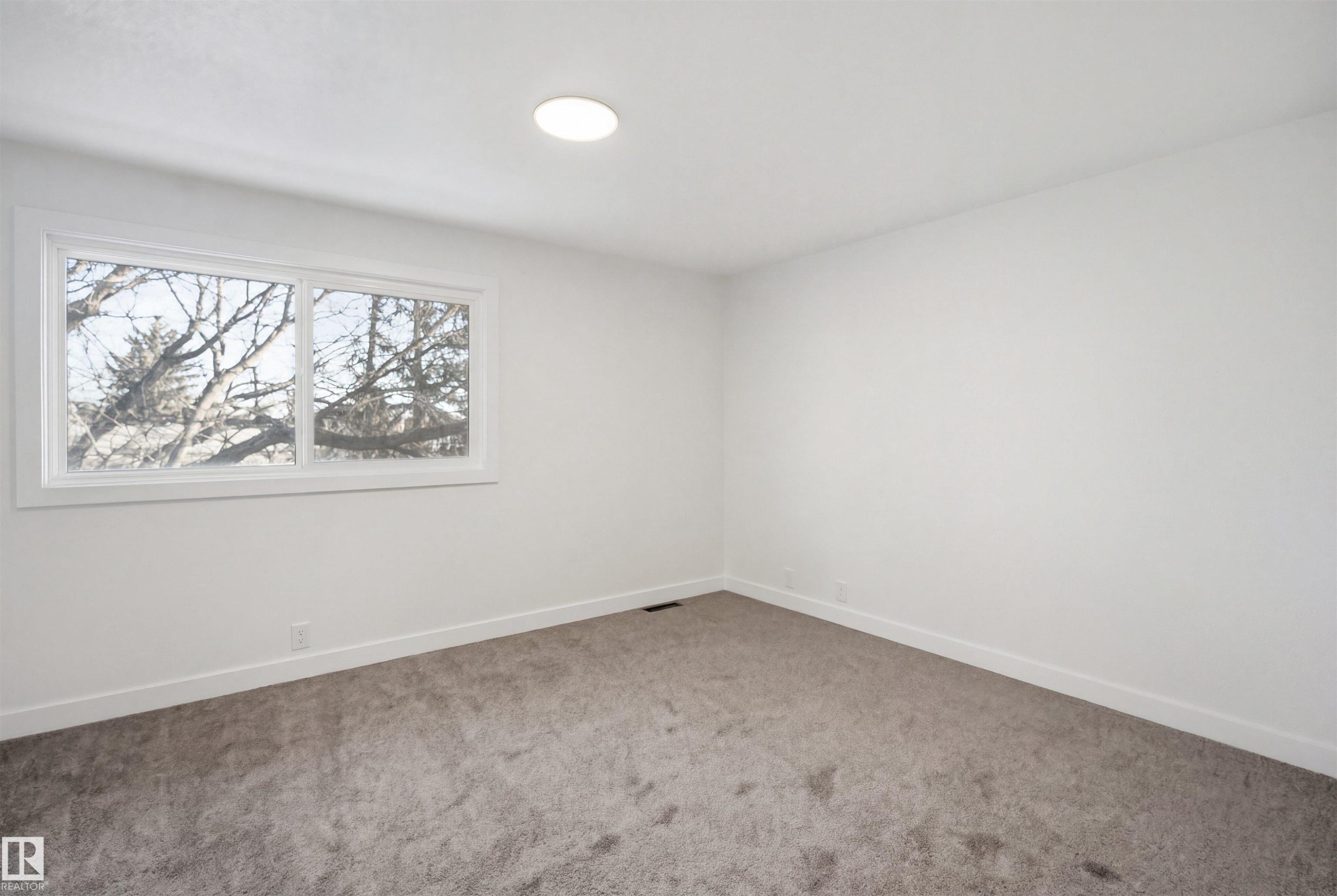 Spacious room featuring neutral carpeting, white walls, a large window, white trim, and a recessed ceiling light - 1706 37 Street, Edmonton, AB - Indoor Photo Showing Other Room
