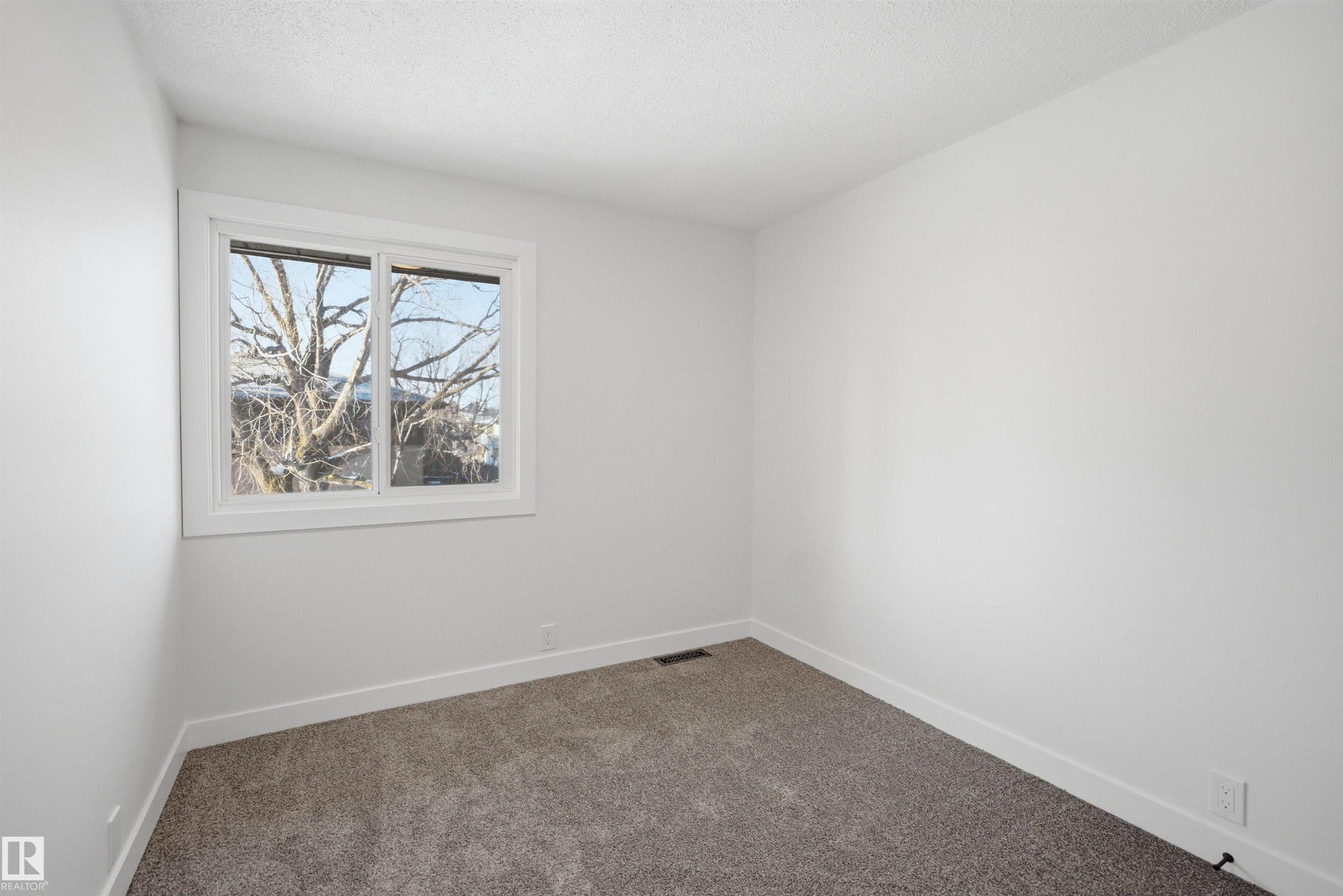 Bright room featuring a window with white trim, neutral carpet, white walls, and white baseboards - 1706 37 Street, Edmonton, AB - Indoor Photo Showing Other Room