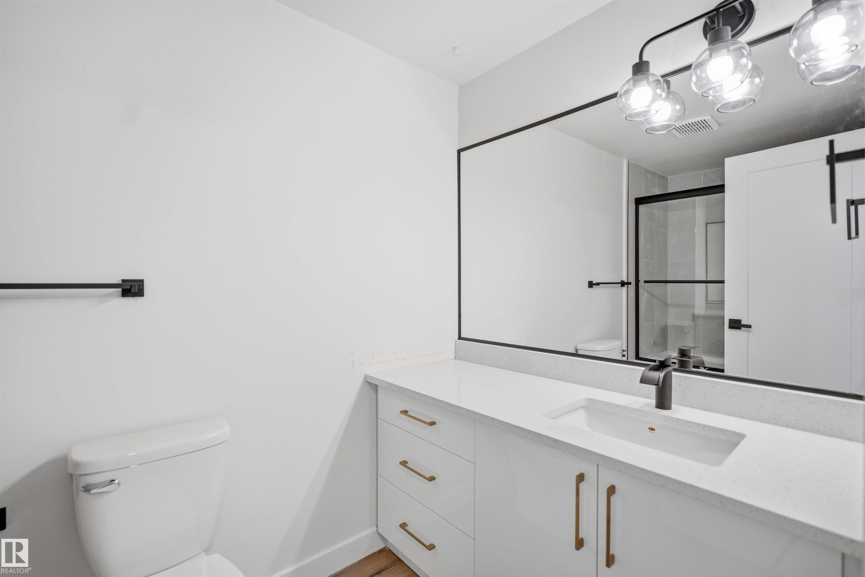 Bathroom featuring a white vanity with gold-tone hardware, a white countertop, and an undermount sink with a matte black faucet - 1706 37 Street, Edmonton, AB - Indoor Photo Showing Bathroom