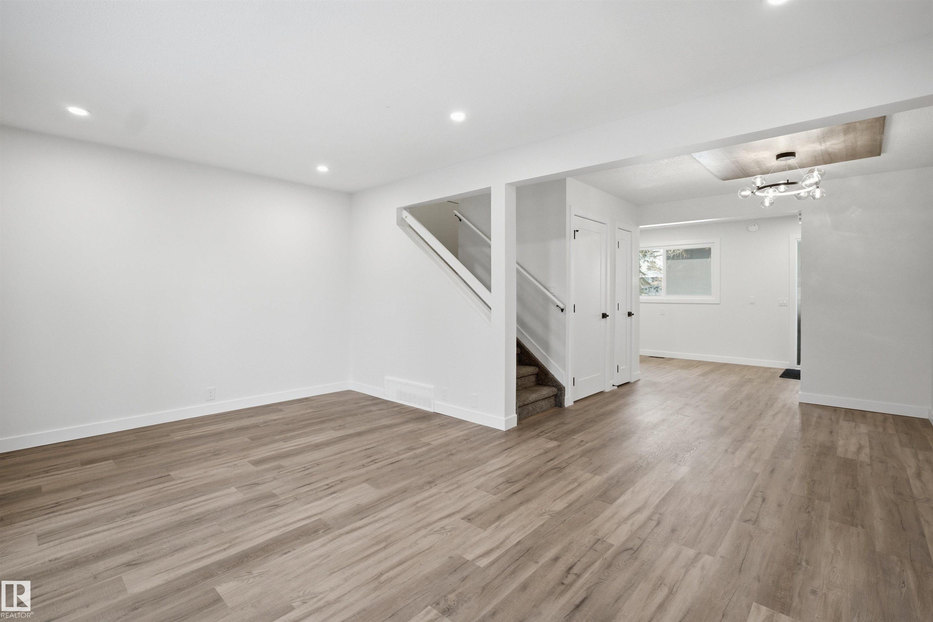 Spacious open-concept living area featuring wood-finish flooring, recessed lighting, and a modern chandelier - 1706 37 Street, Edmonton, AB - Indoor Photo Showing Other Room