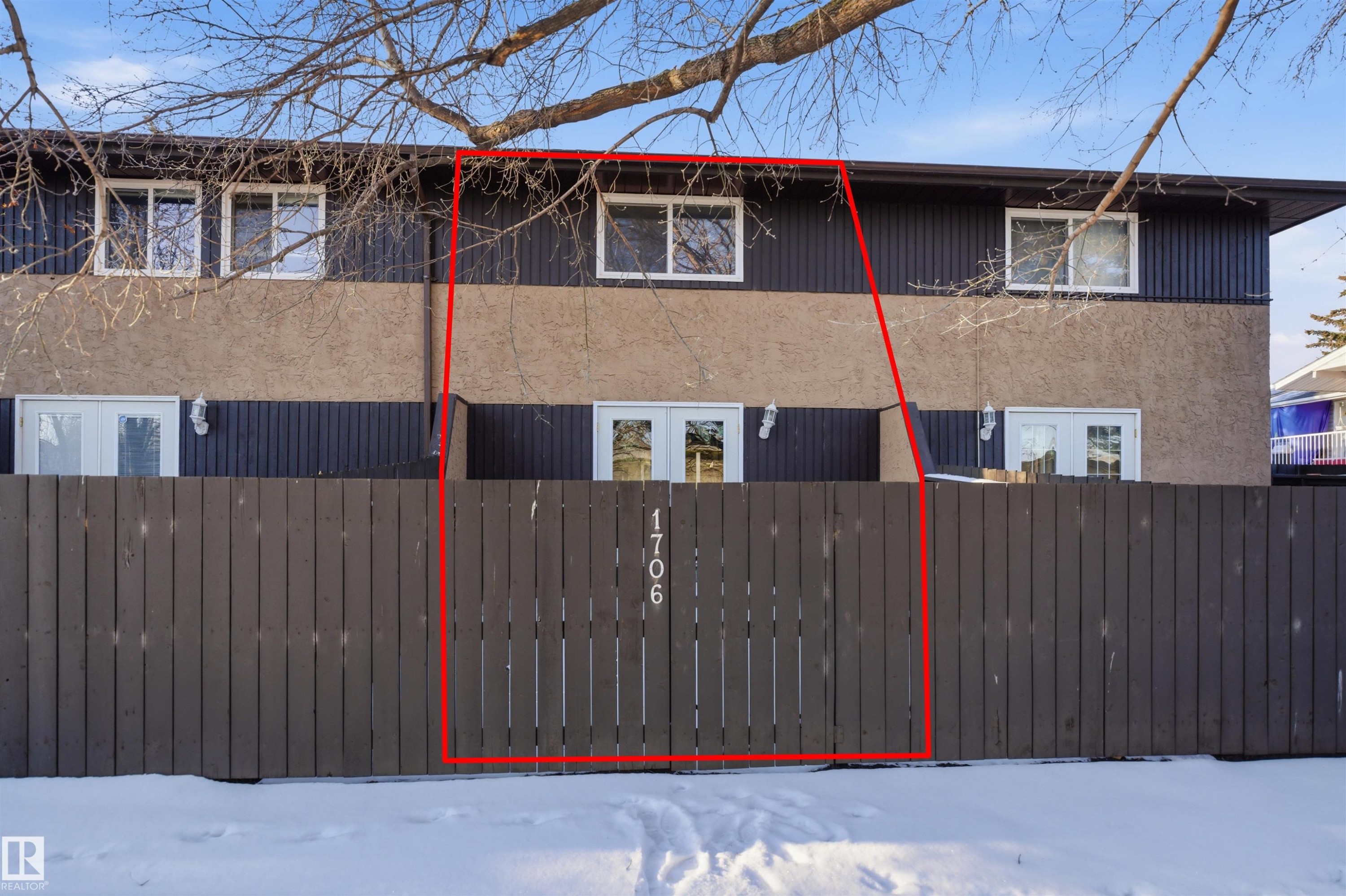 Townhome exterior featuring a private wood fence, ground-level patio doors, and upper-level windows - 1706 37 Street, Edmonton, AB - Outdoor