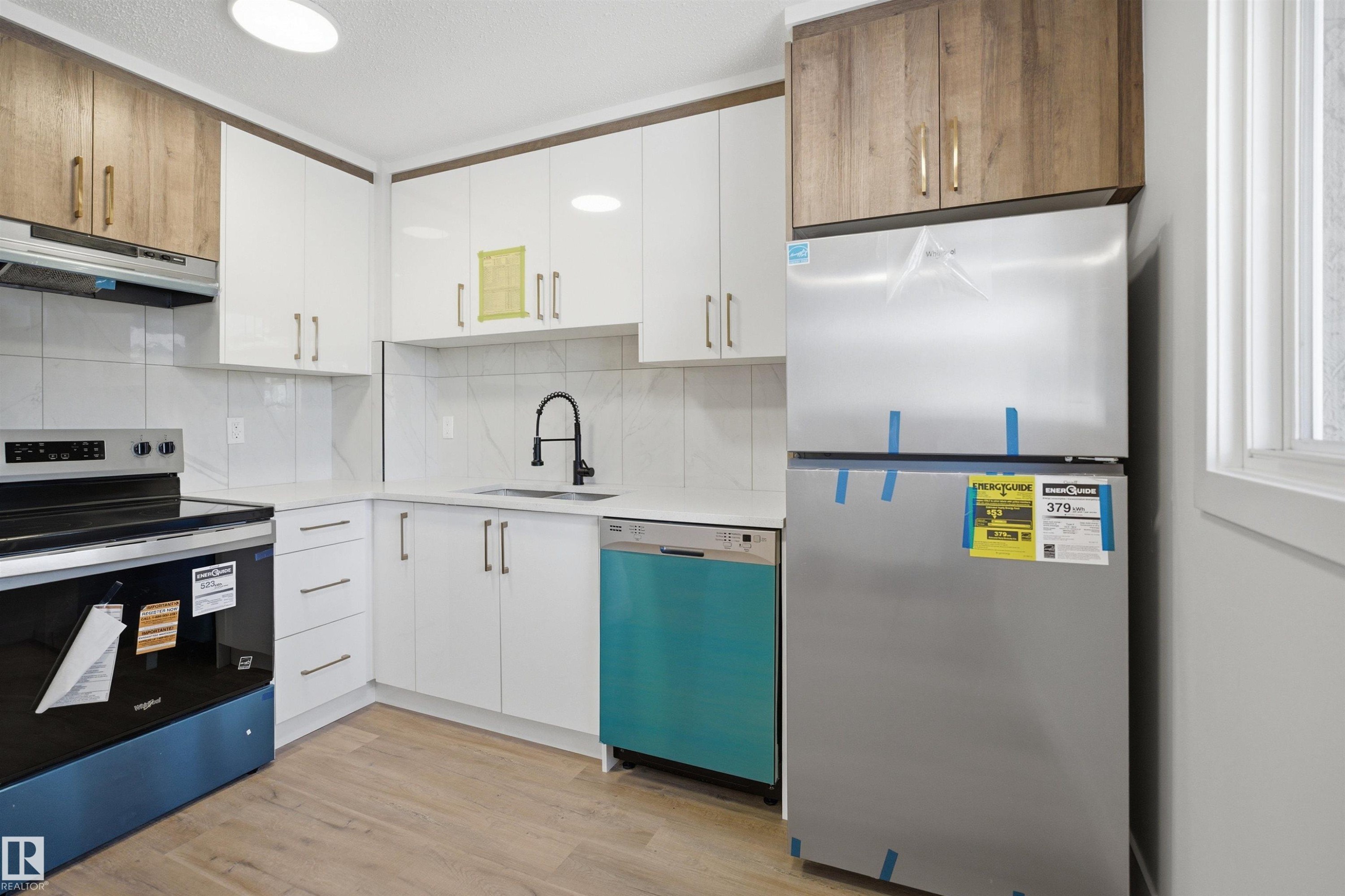 Modern kitchen featuring white cabinetry complemented by wood-finish upper cabinets - 1706 37 Street, Edmonton, AB - Indoor Photo Showing Kitchen