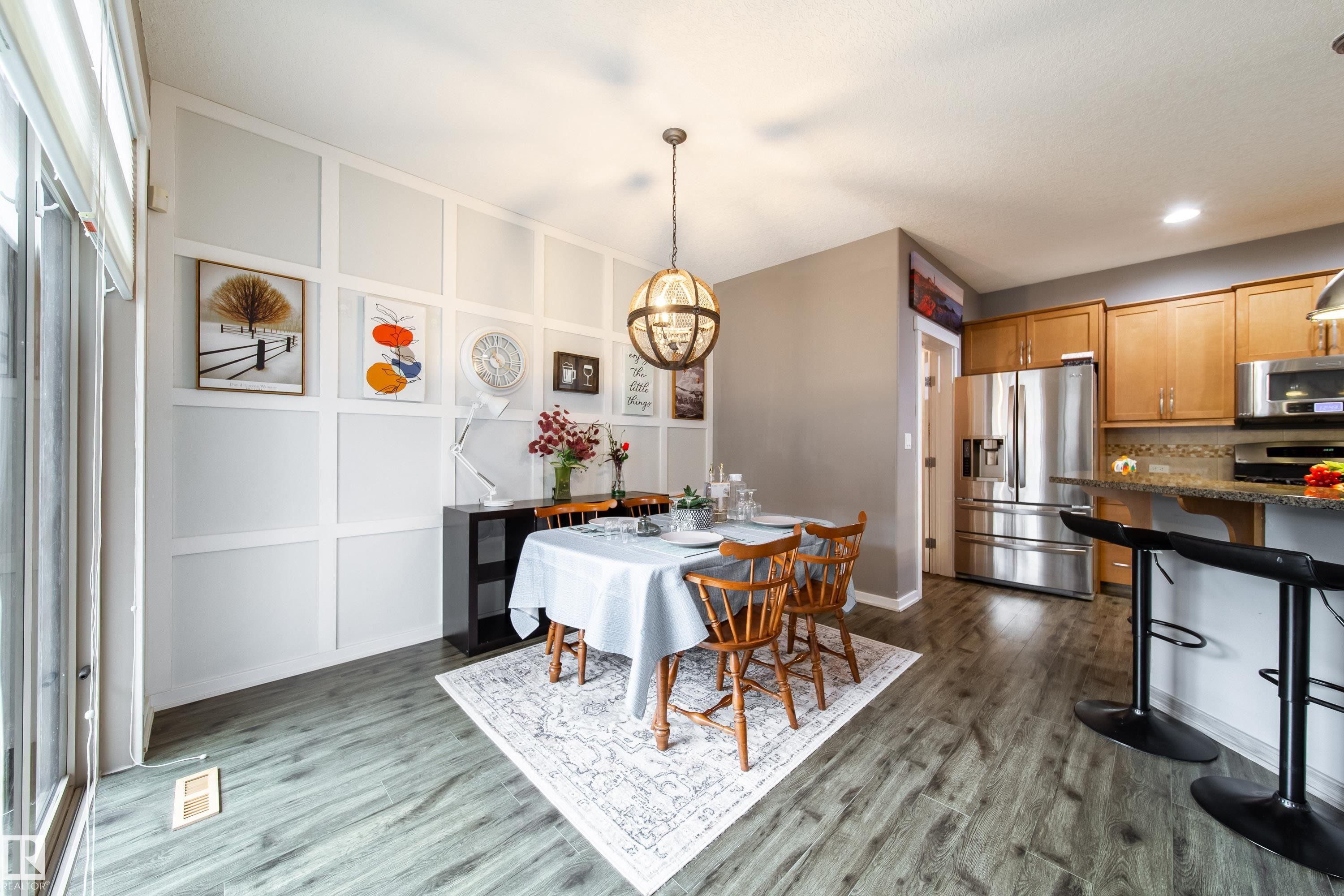 Dining area featuring a decorative accent wall, wood-finish flooring, and a contemporary chandelier - 2016 125 Street, Edmonton, AB - Indoor