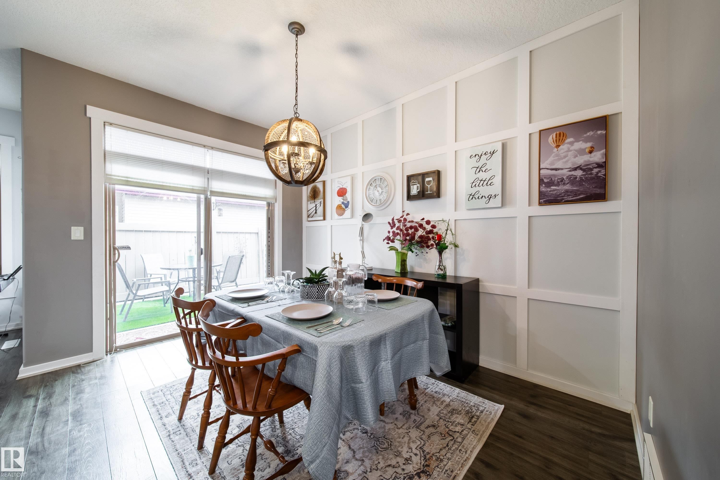 Dining area featuring board and batten accent wall, wood-finish flooring, and a contemporary spherical chandelier - 2016 125 Street, Edmonton, AB - Indoor Photo Showing Dining Room