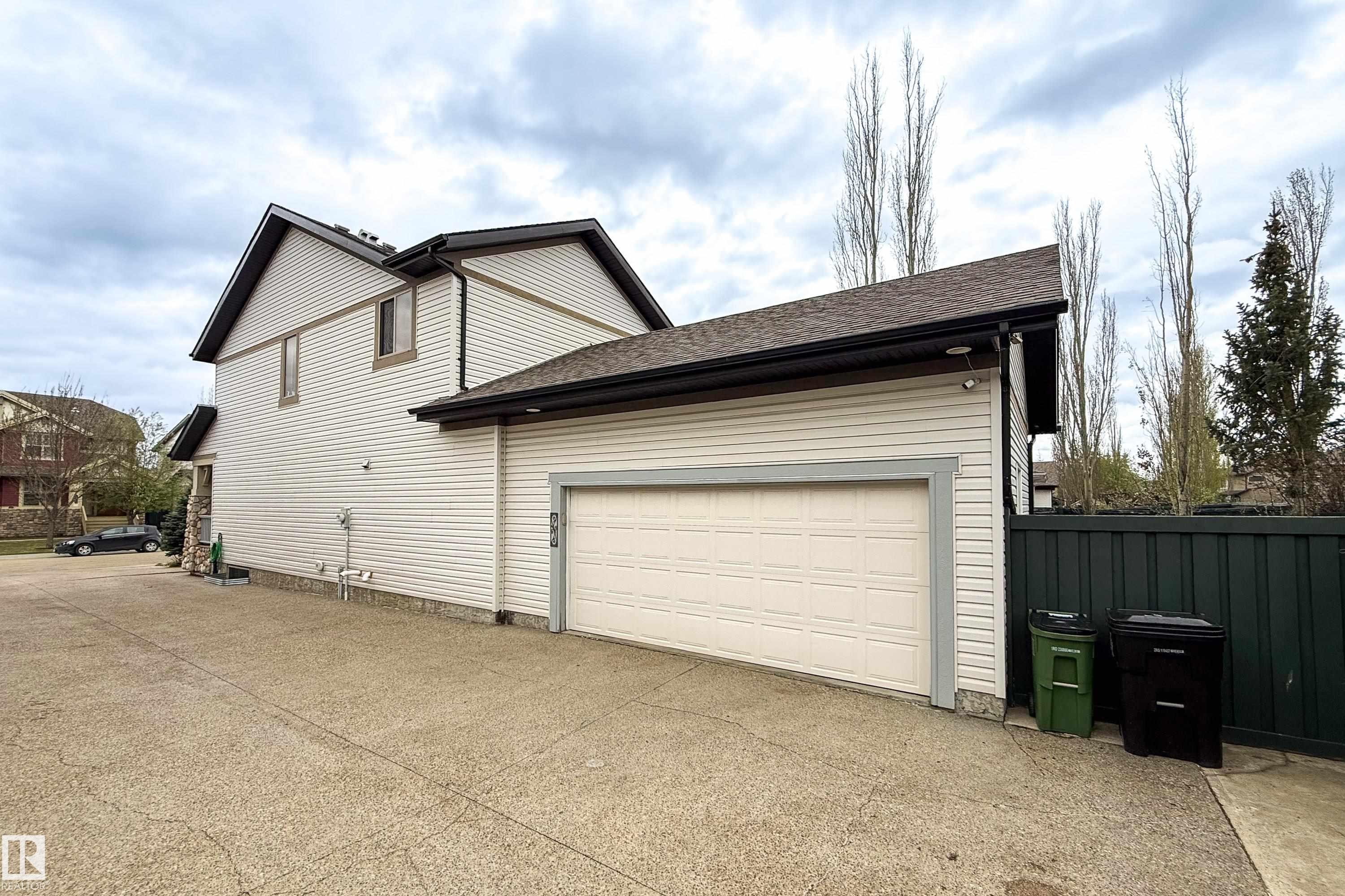 Attached garage with a light-colored sectional door, asphalt shingle roofing, and light-colored horizontal siding - 2016 125 Street, Edmonton, AB - Outdoor With Exterior