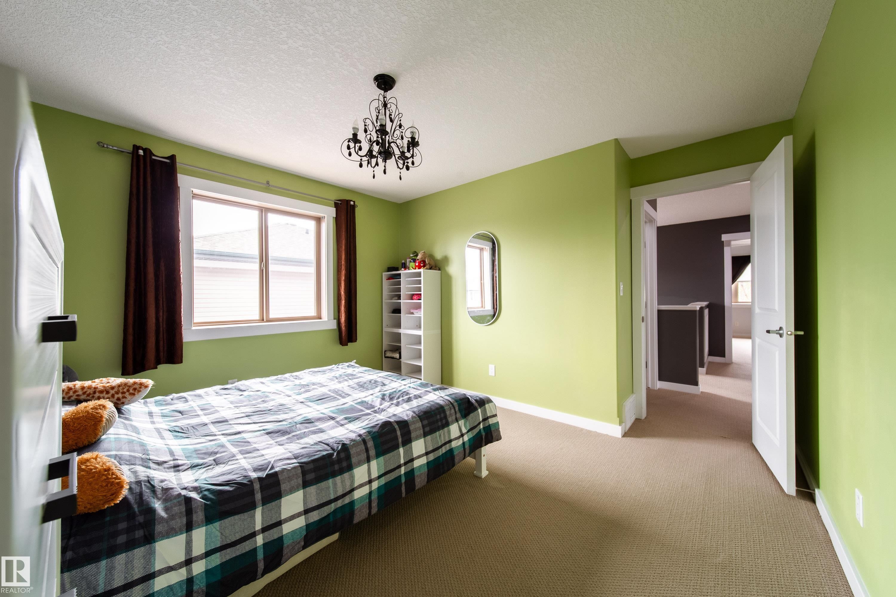 Room featuring light green walls, a single window with brown curtains, a black chandelier, and neutral-toned carpeting - 2016 125 Street, Edmonton, AB - Indoor Photo Showing Bedroom