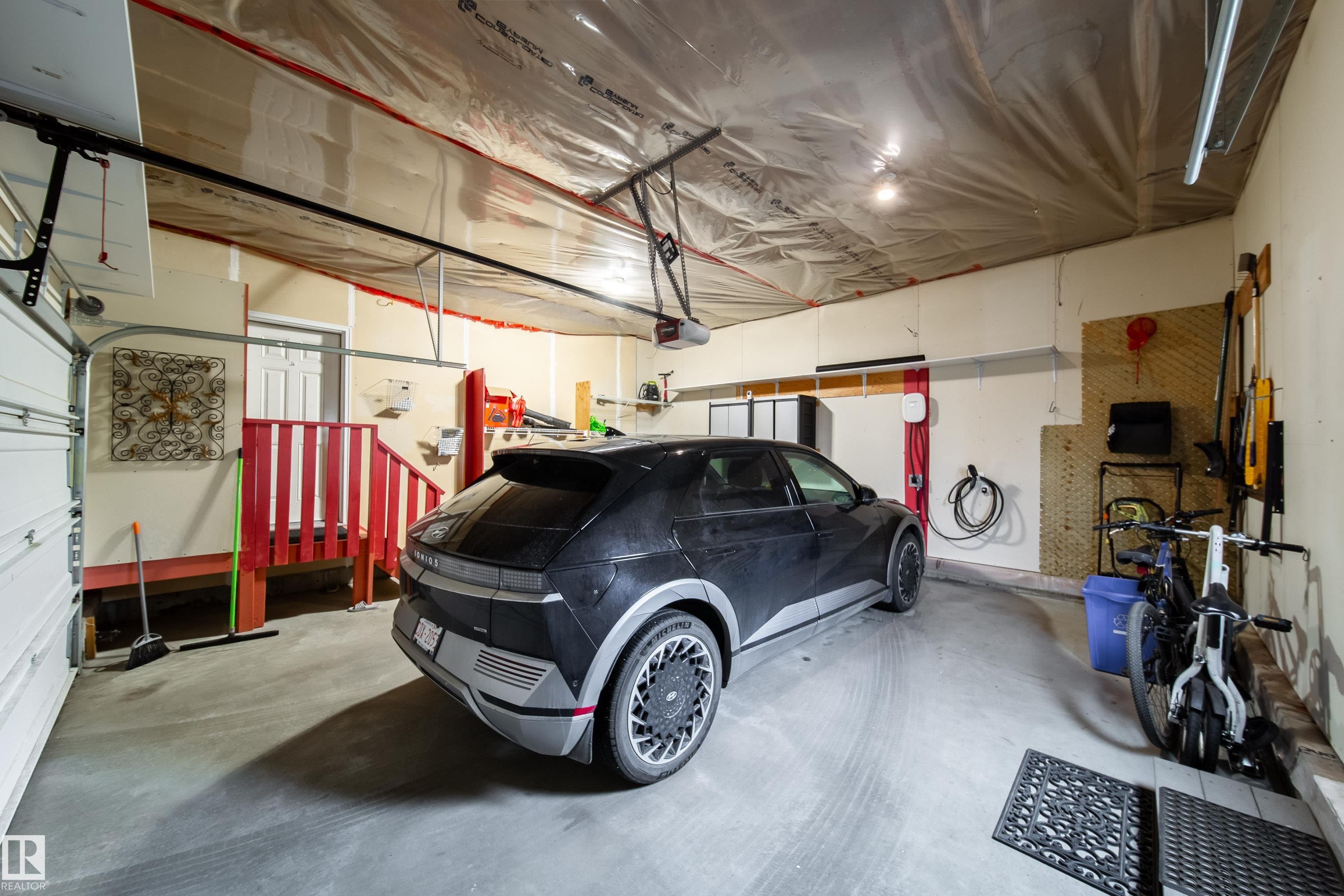 Spacious garage featuring a concrete floor, built-in storage cabinetry, overhead lighting, and a dedicated EV charging station - 2016 125 Street, Edmonton, AB - Indoor Photo Showing Garage