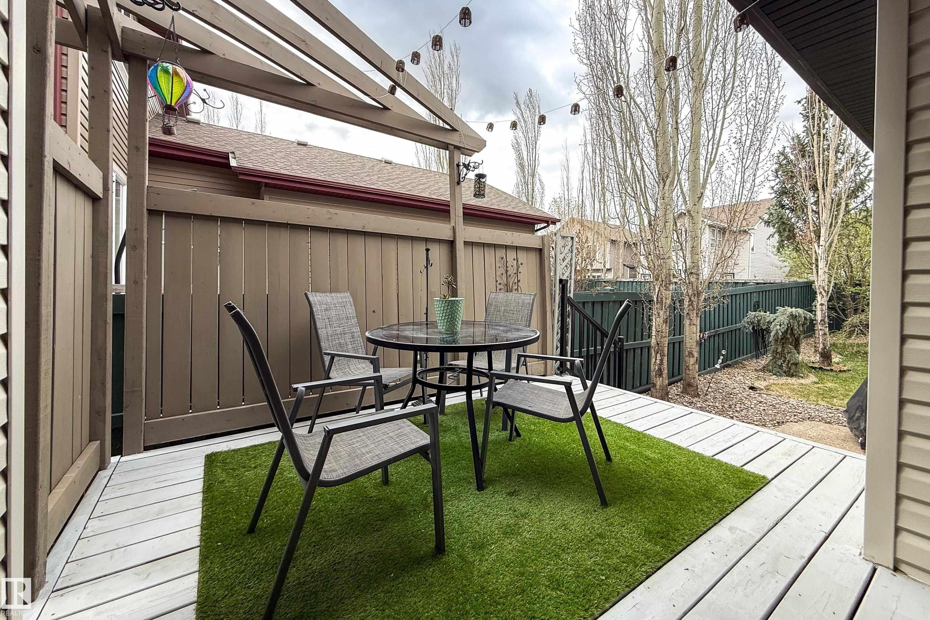 Outdoor patio featuring a pergola, string lights, artificial turf, wood-finish decking, and a privacy fence - 2016 125 Street, Edmonton, AB - Outdoor With Deck Patio Veranda With Exterior